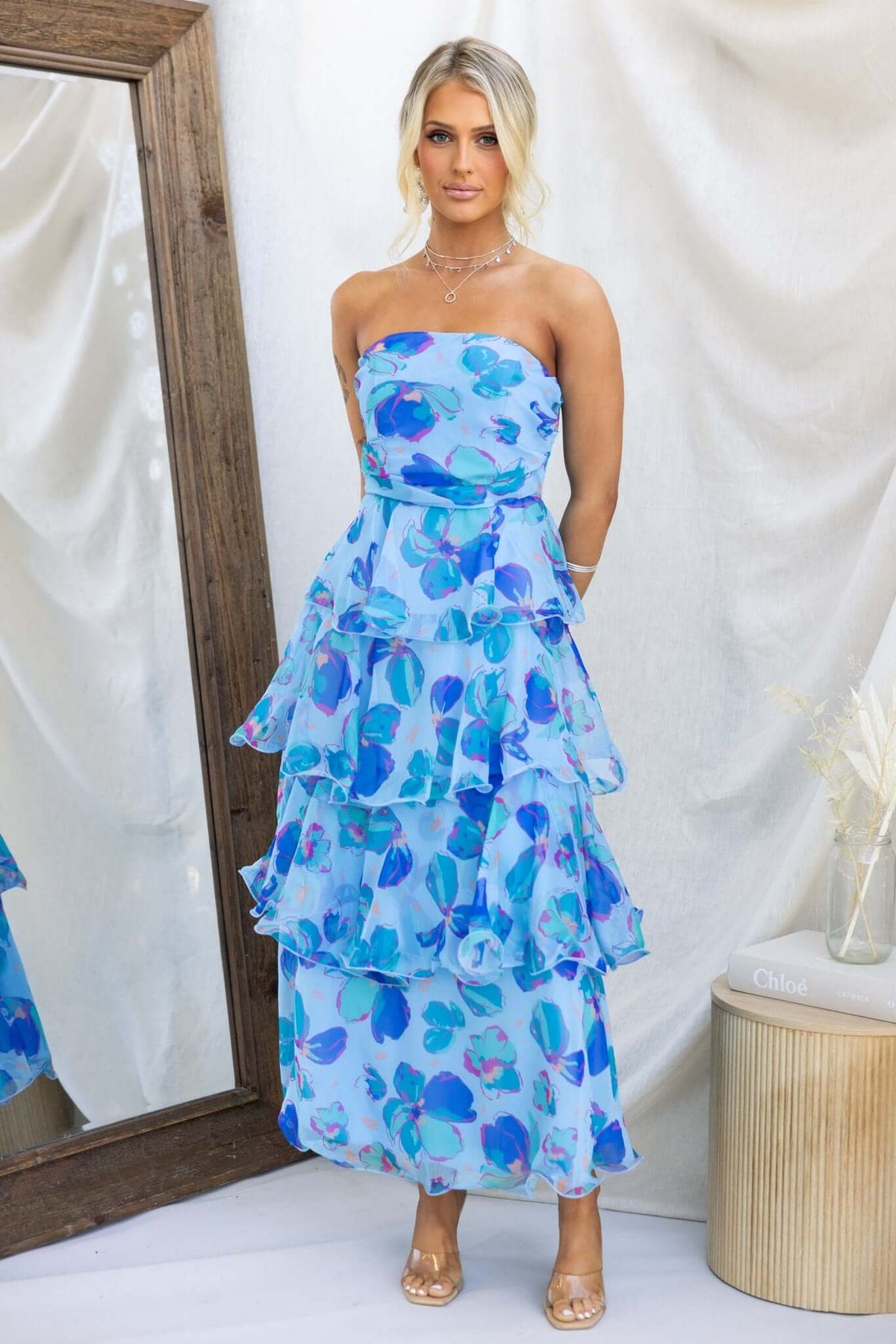 Terrace Maxi Dress in blue floral design with layered ruffles, model stands in front of a mirror.