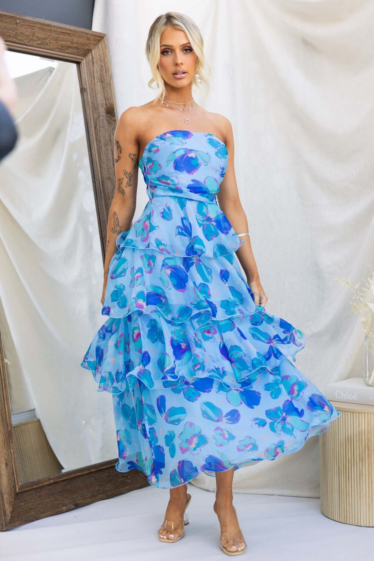 Model wearing a blue Terrace Maxi Dress with floral design and ruffles, perfect for summer events.
