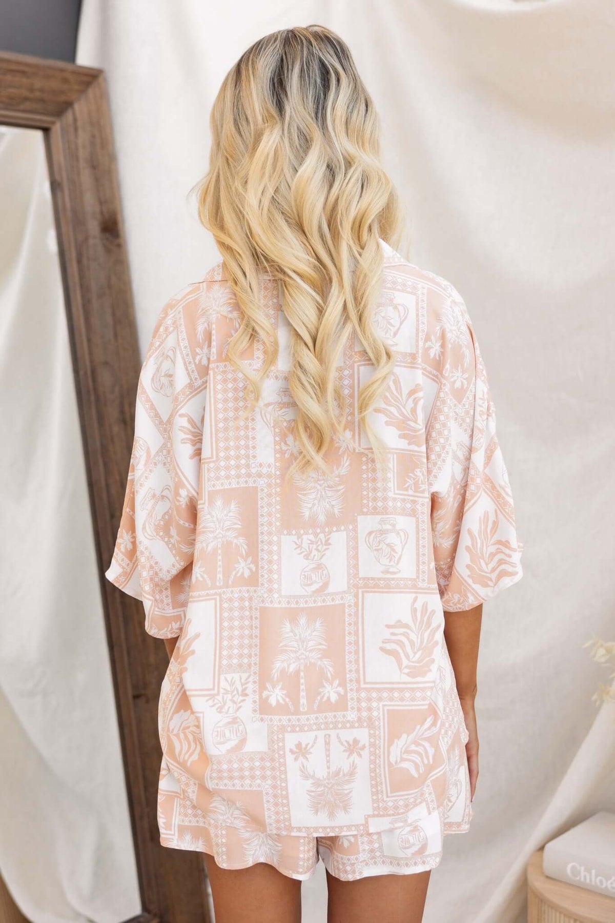 Model wearing the Lazy Sunday Top featuring a pastel patterned design, shown from the back with flowing hair.
