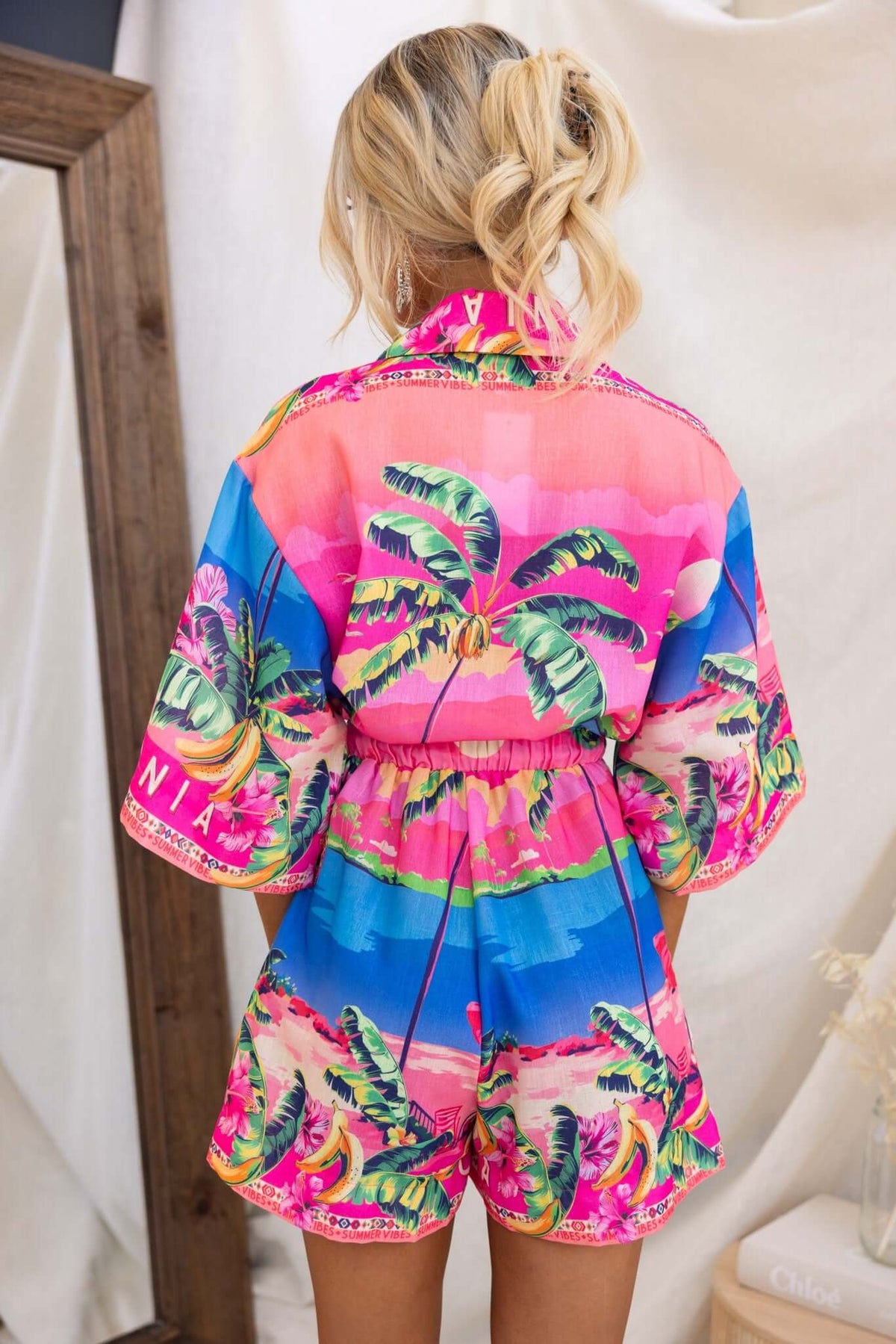 Back view of a colorful Holiday Mode Playsuit featuring palm tree prints and a relaxed fit.