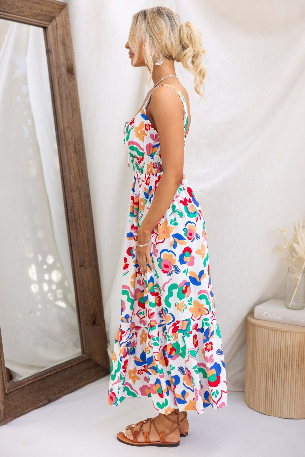 Model wearing the Skipper Midi Dress with colorful floral print, adjustable straps, and a tie at the bust.
