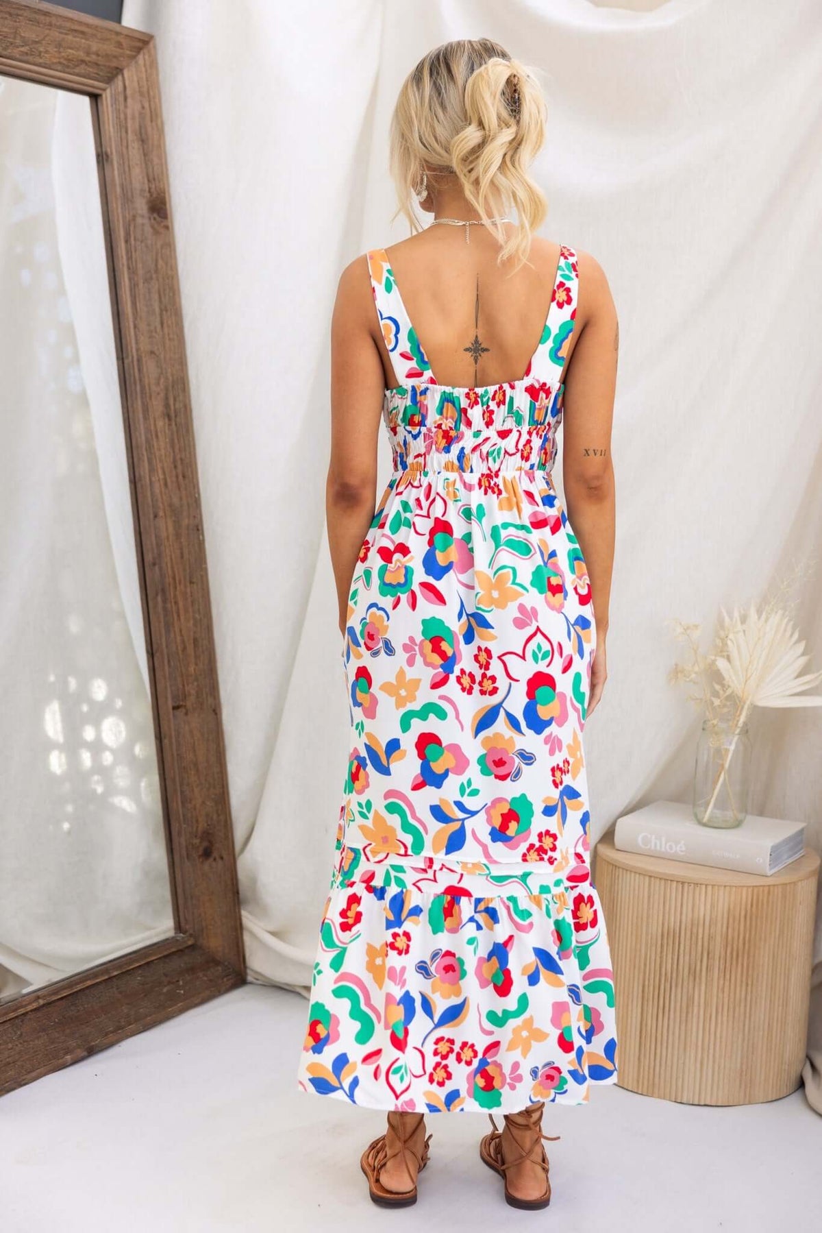 Back view of a woman in a colorful Skipper Midi Dress featuring adjustable straps and a tiered skirt.