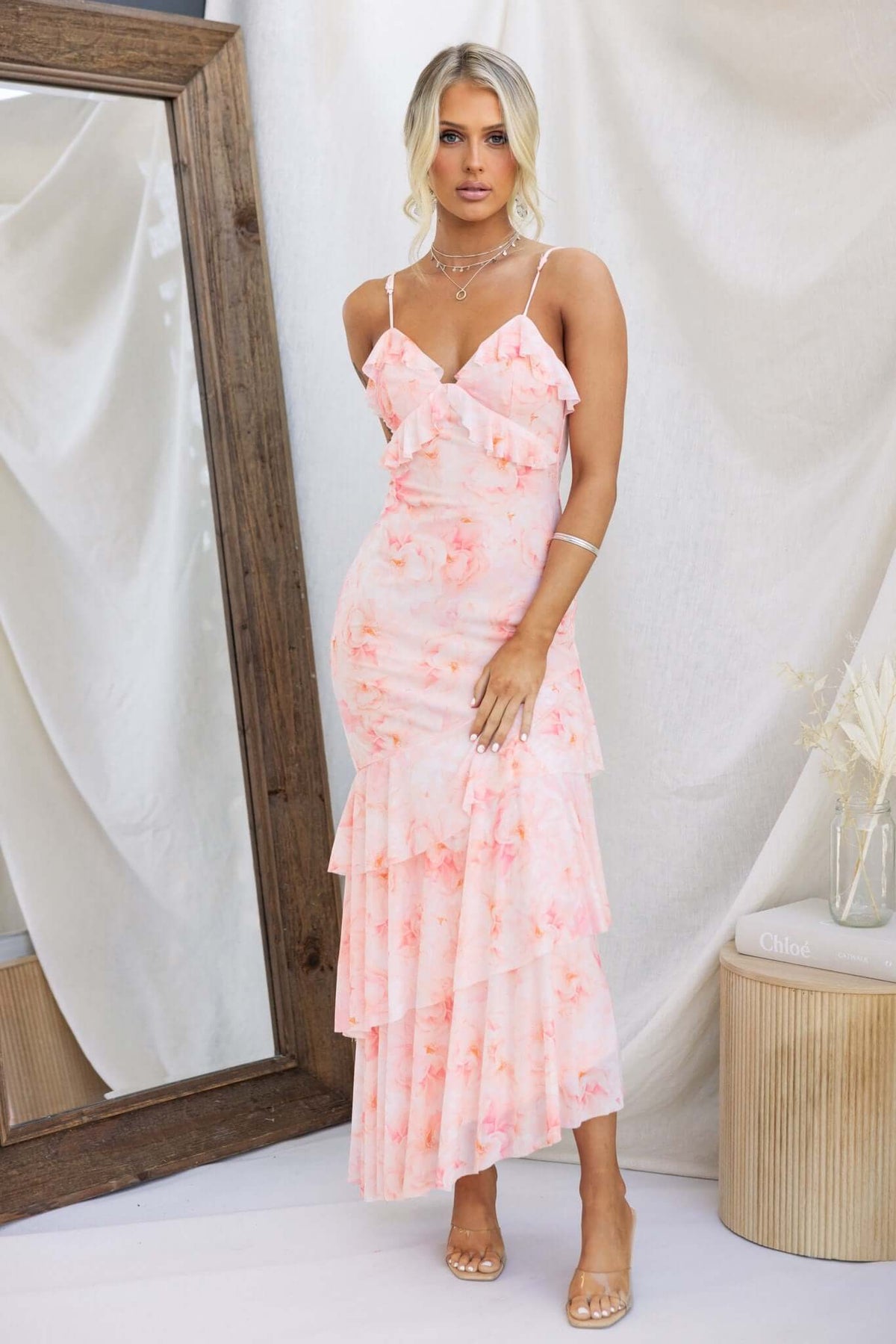 Vessy Maxi Dress in pink floral design with adjustable straps and tiered asymmetrical hemline, styled elegantly.