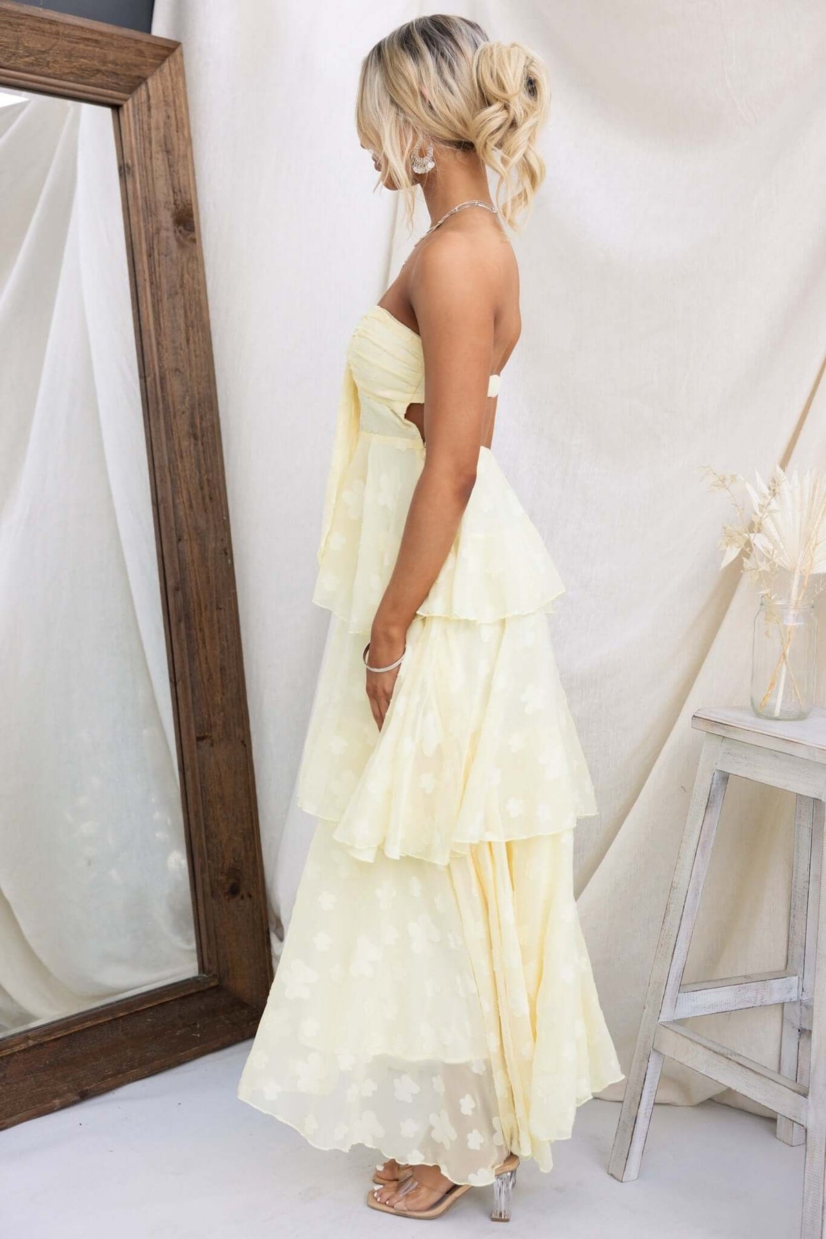 Model wearing a Soft Whispers Maxi Dress in soft yellow, showcasing a tiered ruffle skirt and elegant floral design.