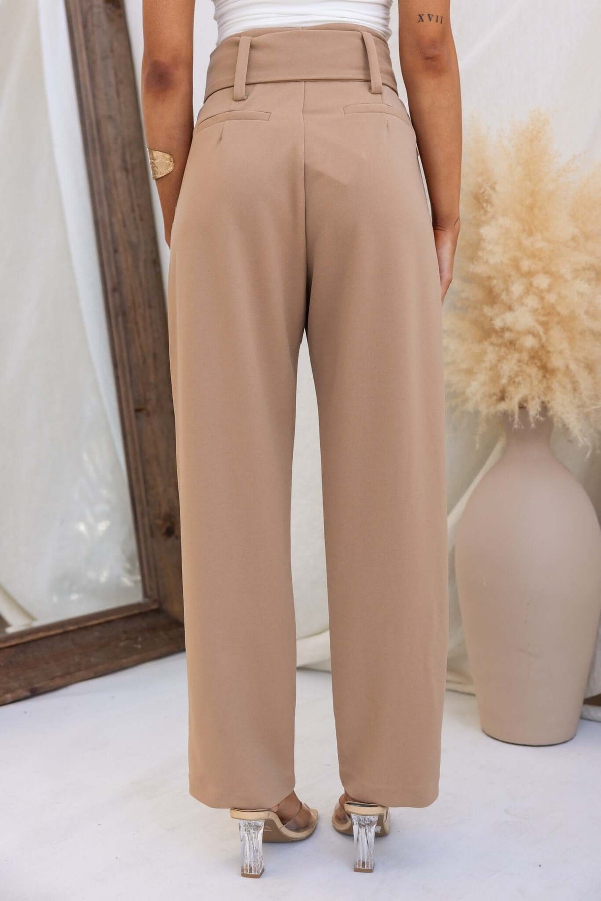 Back view of high waist Huffington Pants in taupe with removable belt and pockets, styled with a modern touch.