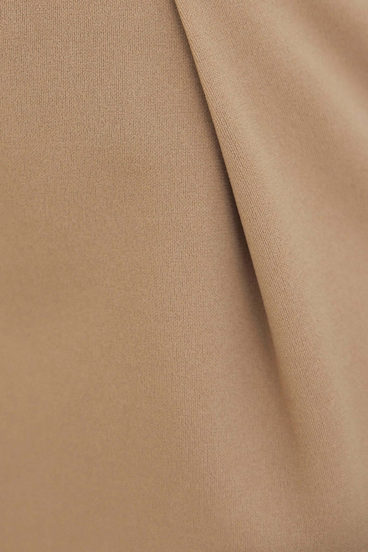 Close-up of the fabric texture of Huffington Pants in a warm beige tone, highlighting its softness and stretch.