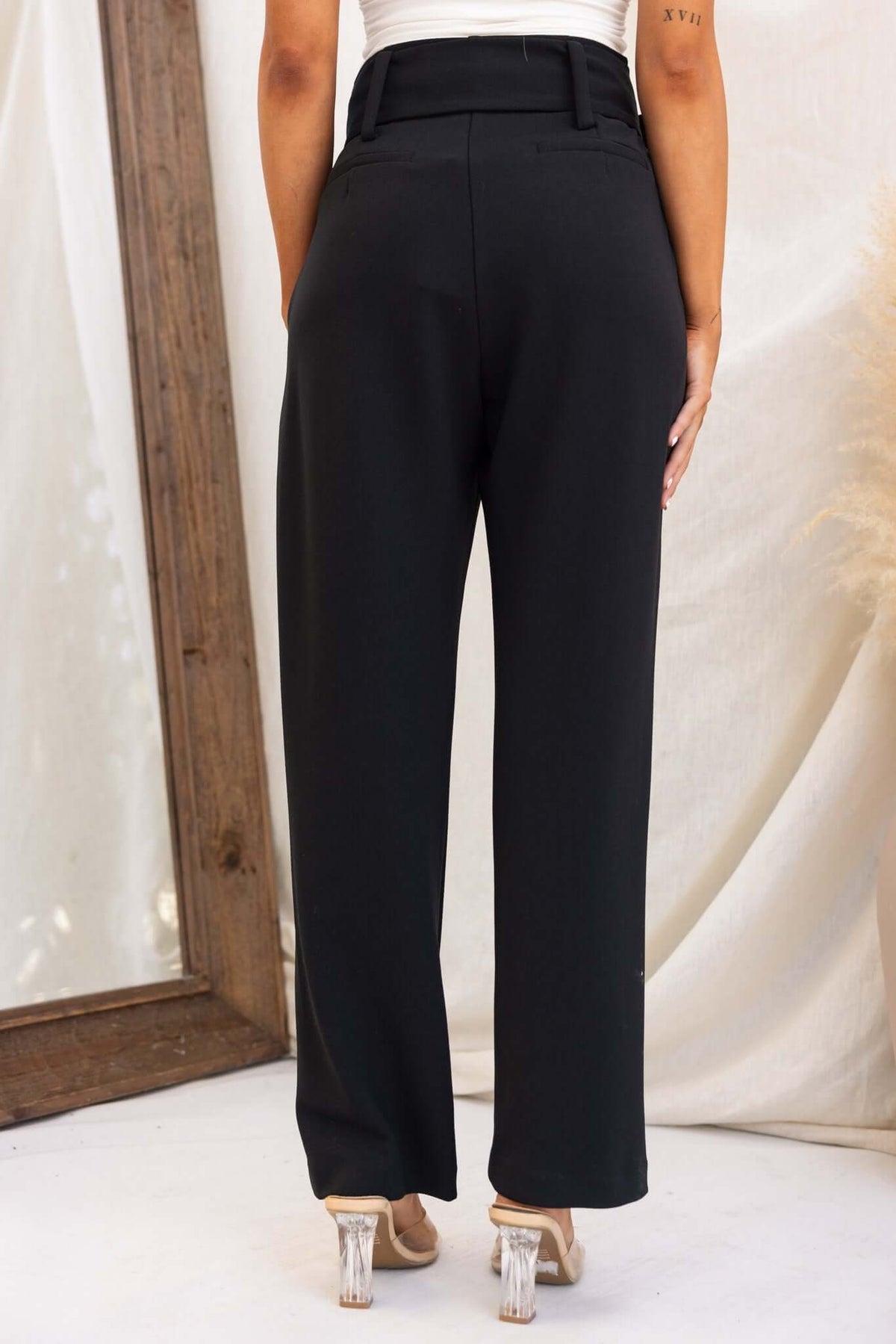 Back view of Huffington Pants featuring a high waist, removable belt, and pockets, styled with clear heels.