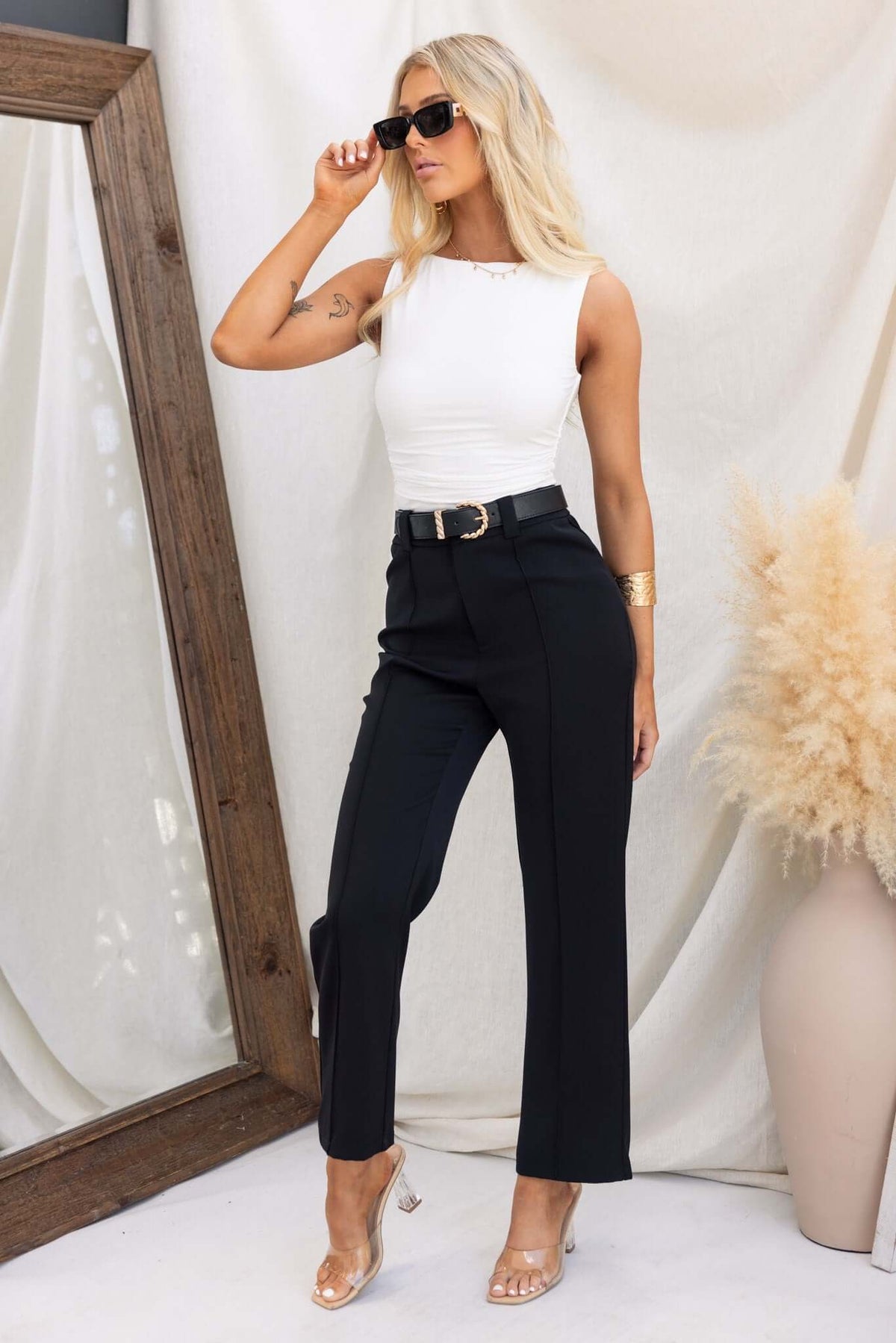 Model wearing black Columbus Pants with a white top and sunglasses, showcasing mid-high waist fit and stylish look.