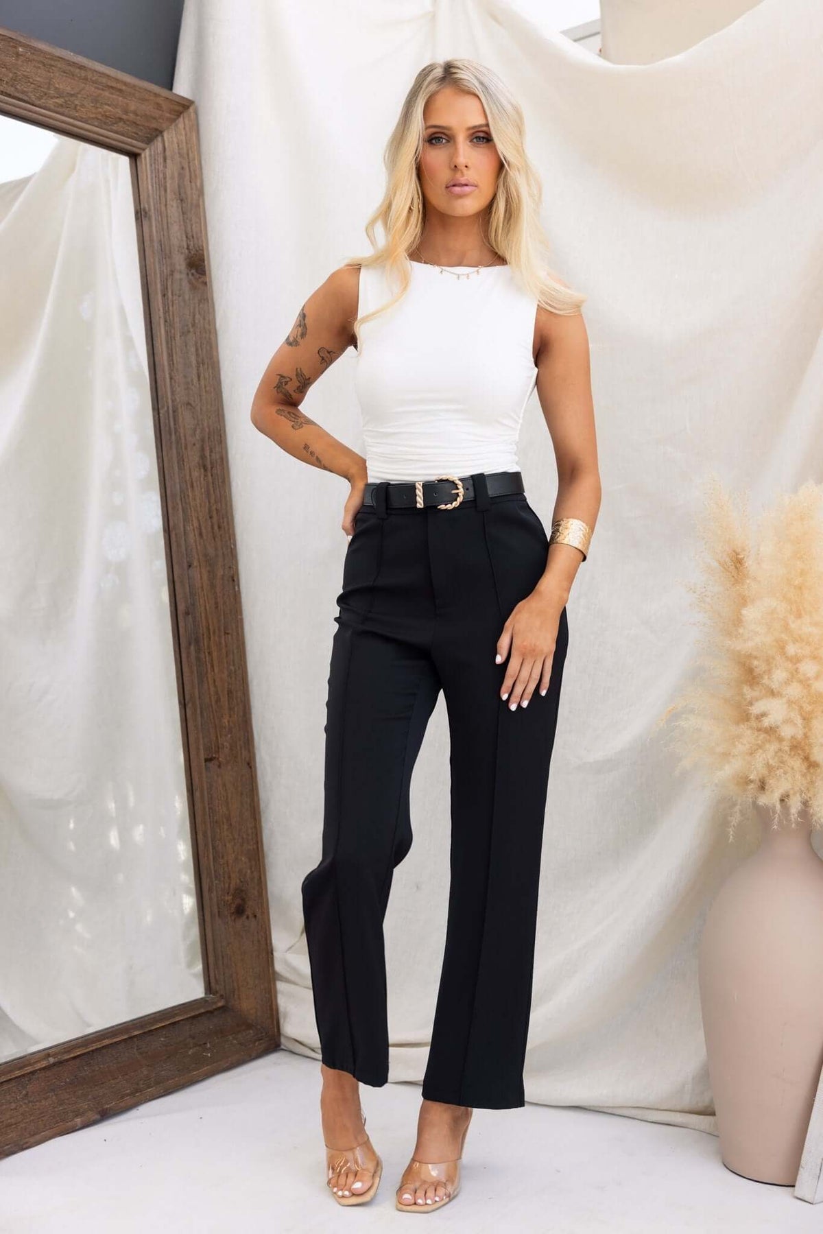 Model wearing Columbus Pants, black mid-high waist fit, paired with a white top and accessories, showcasing a stylish look.