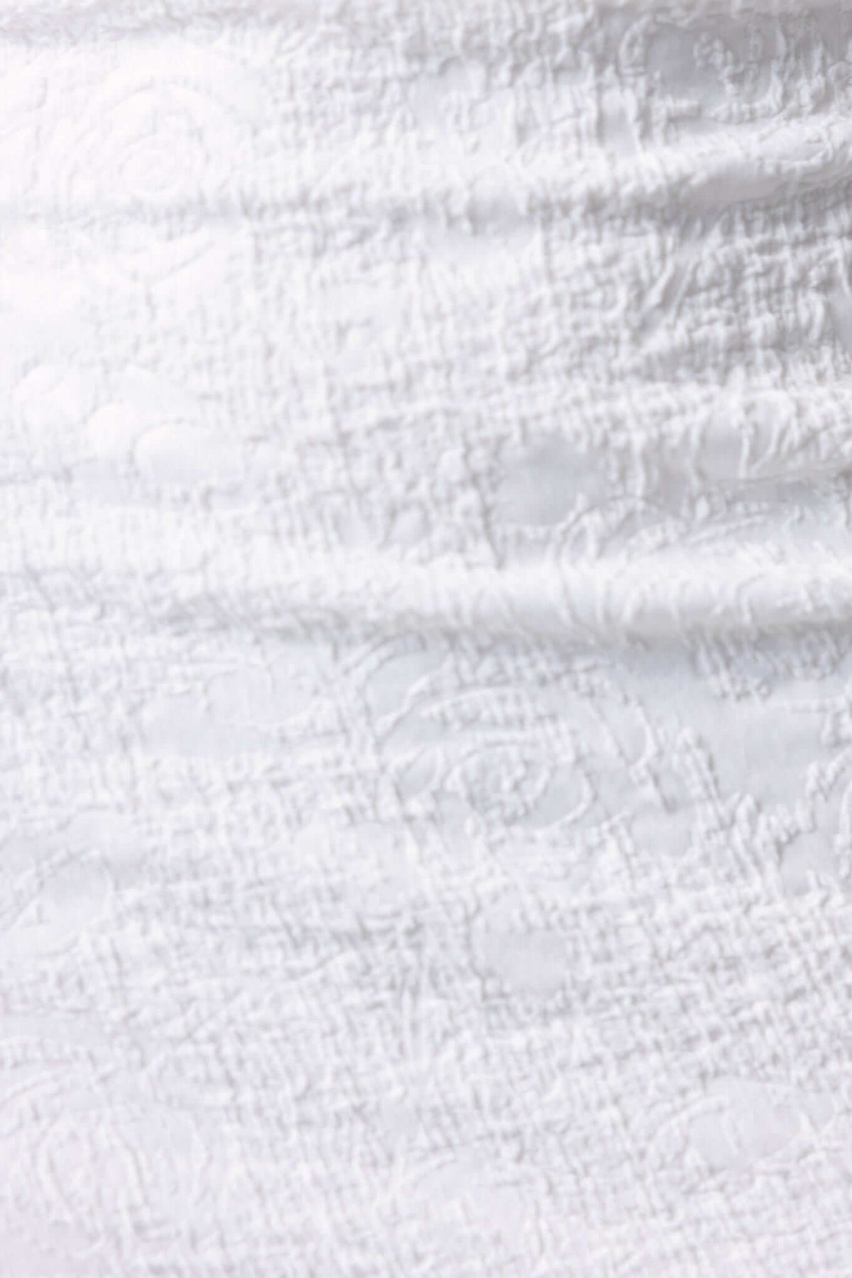 Textured fabric close-up of the Sheridan Midi Dress, showcasing a soft white color with intricate patterns.
