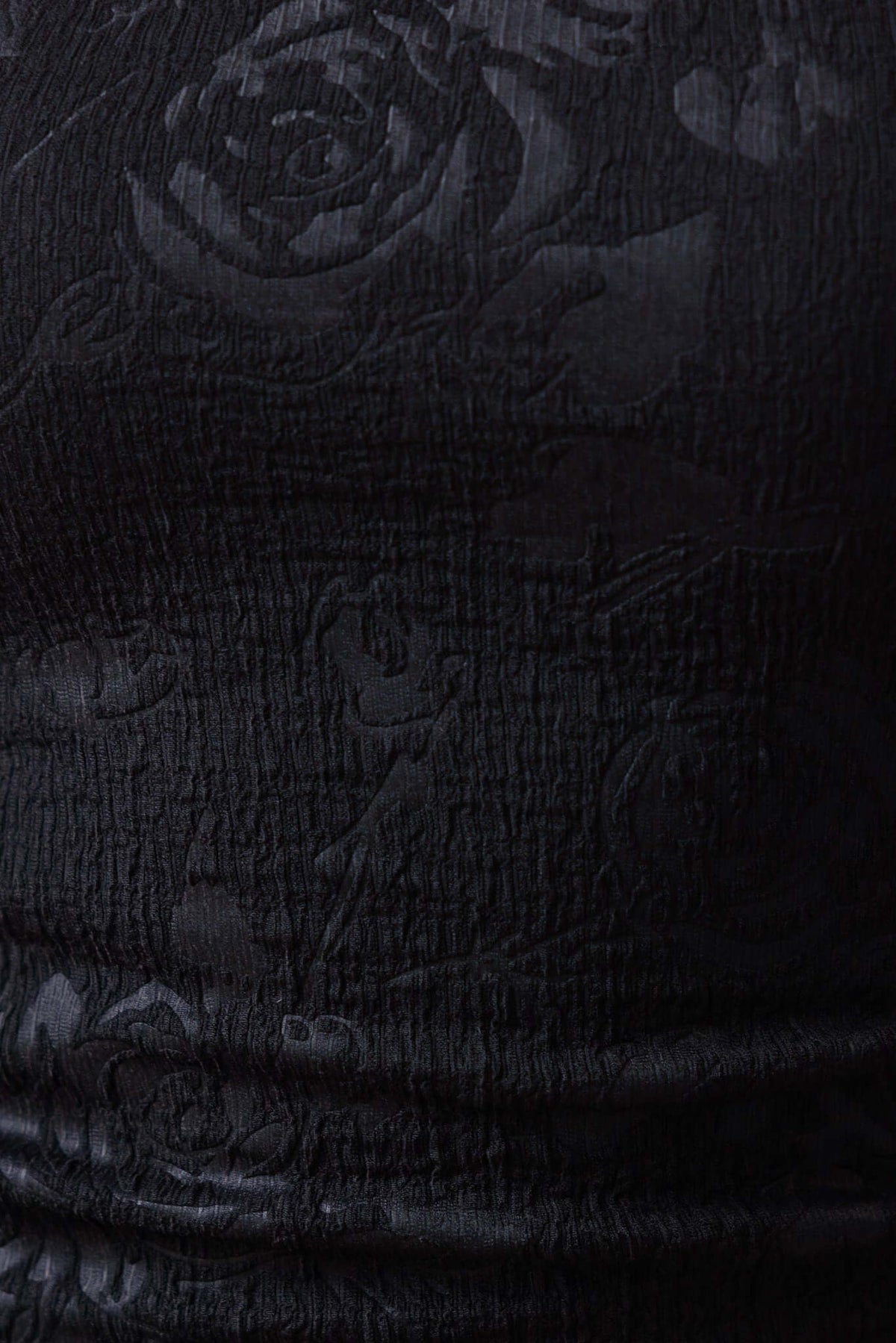 Close-up of textured black fabric featuring a floral pattern, showcasing the ruched detail of the Sheridan Midi Dress.