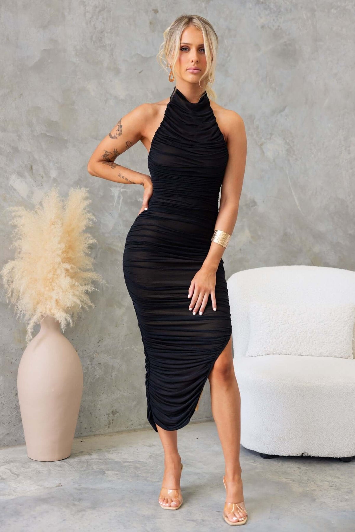 Model wearing a black Gellis Midi Dress with high neckline and asymmetrical hemline, showcasing stylish chiffon material.