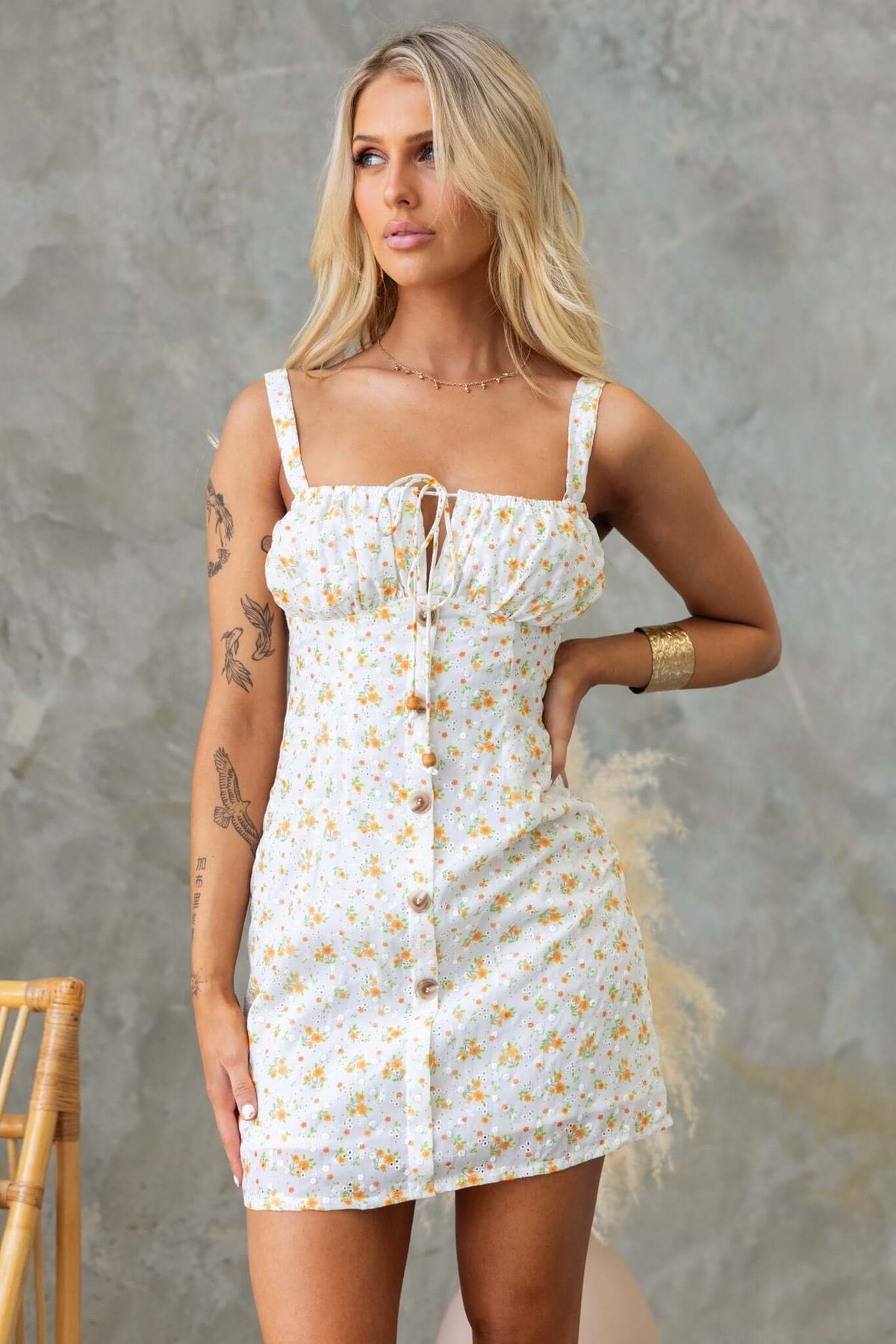 Imaginative dress with floral print, adjustable straps, tie at bust, and faux buttons.