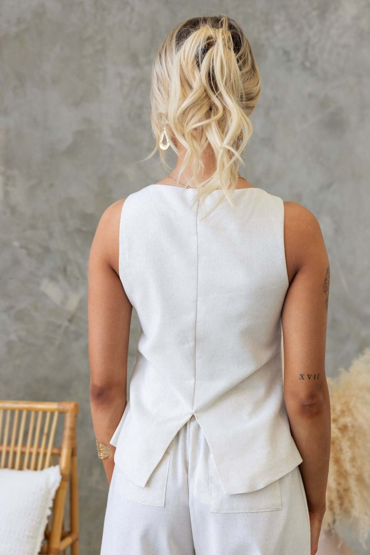 Back view of the Payson Top featuring a button down design and linen-like texture, styled with relaxed trousers.