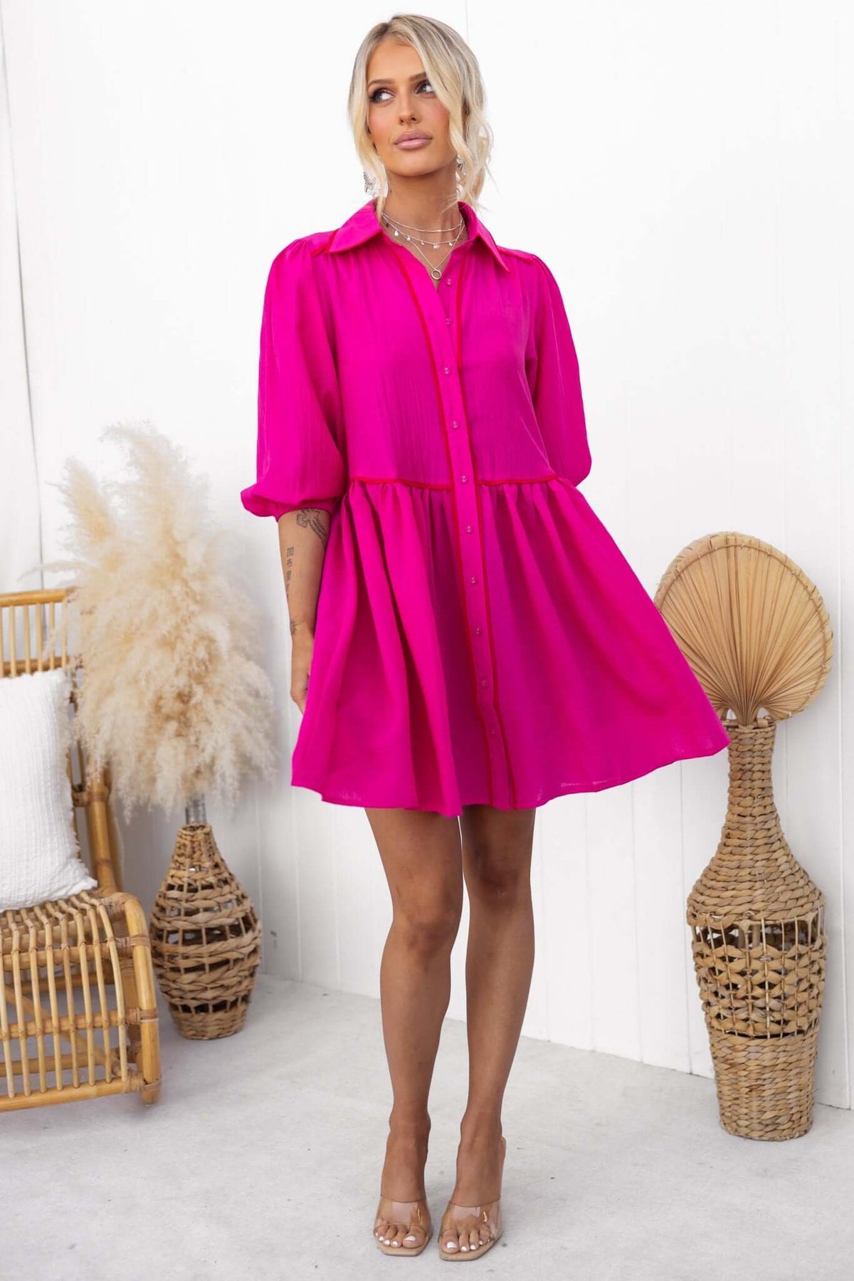Model wearing a vibrant pink Sherbet Dress with button-down front and puff sleeves, styled for a chic look.