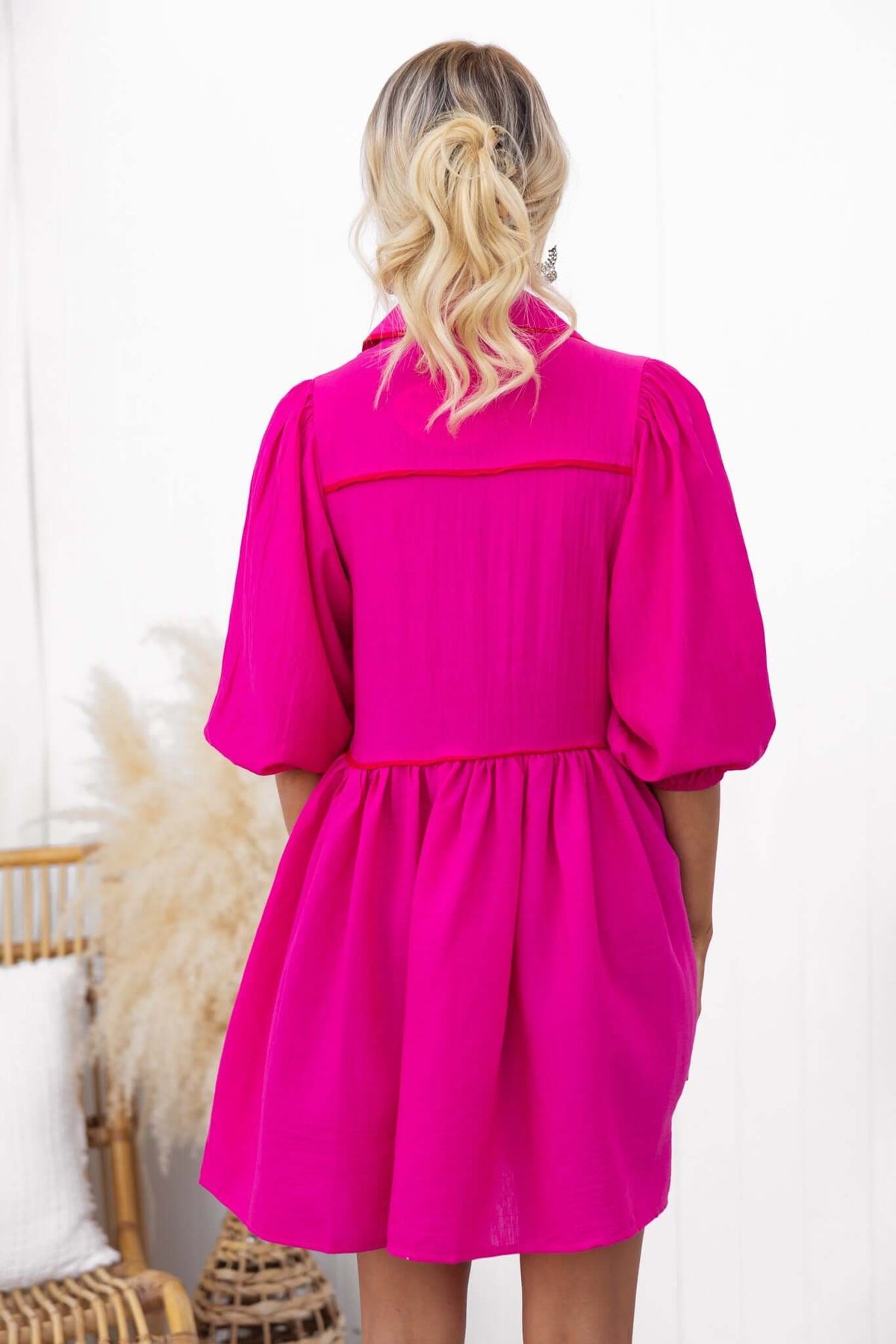 Back view of a vibrant pink sherbet dress featuring puff sleeves and a button-down front.