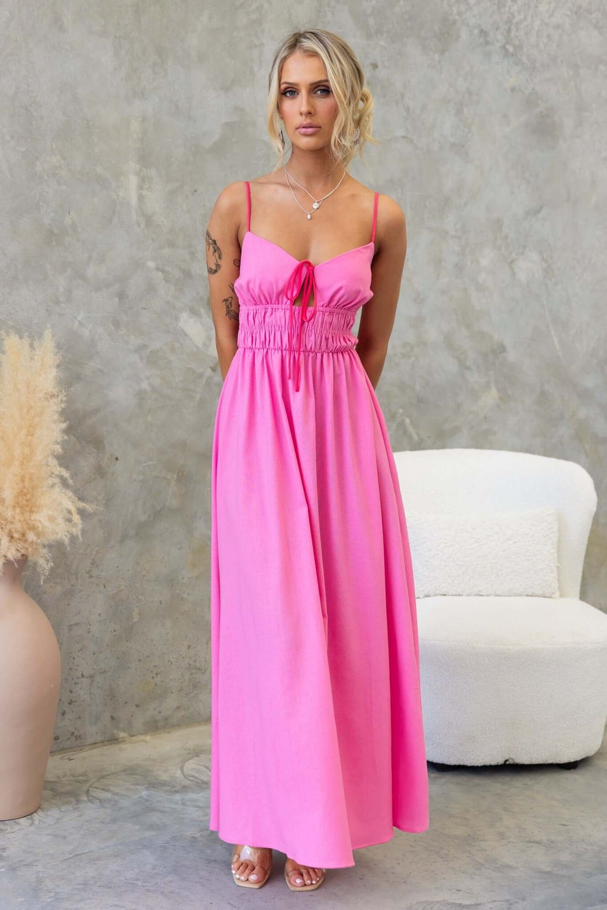 Brooklynn Maxi Dress in bright pink, featuring adjustable straps, tie detail, and elastic waist for a stylish summer look.