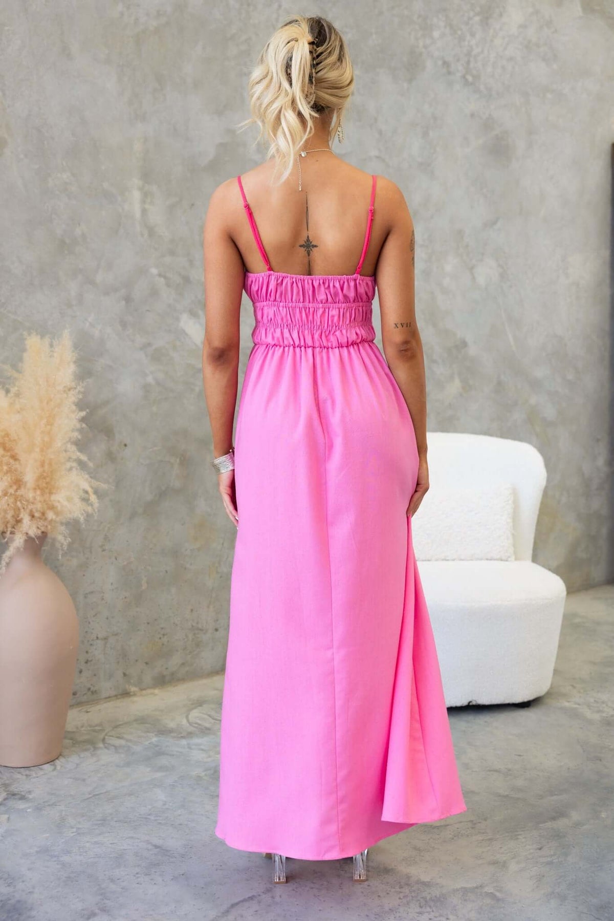 Back view of Brooklynn Maxi Dress in pink with thin straps and elastic waistband, styled in a minimalist setting.