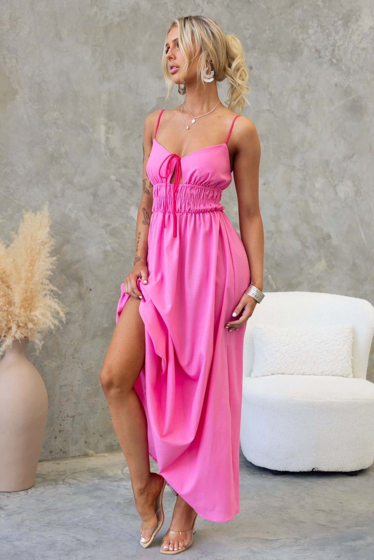 Model wearing a pink Brooklynn Maxi Dress with adjustable straps and tie detail, showcasing its elegant design.