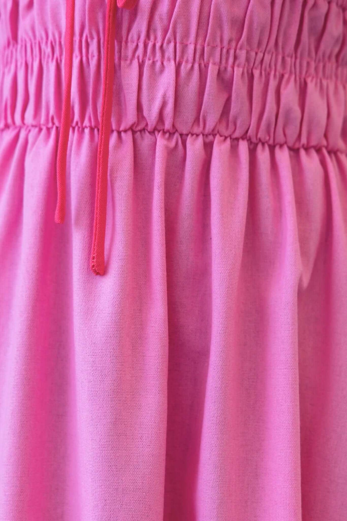Close-up of the pink elastic waist and tie detail of the Brooklynn Maxi Dress, showcasing its soft, non-stretch material.