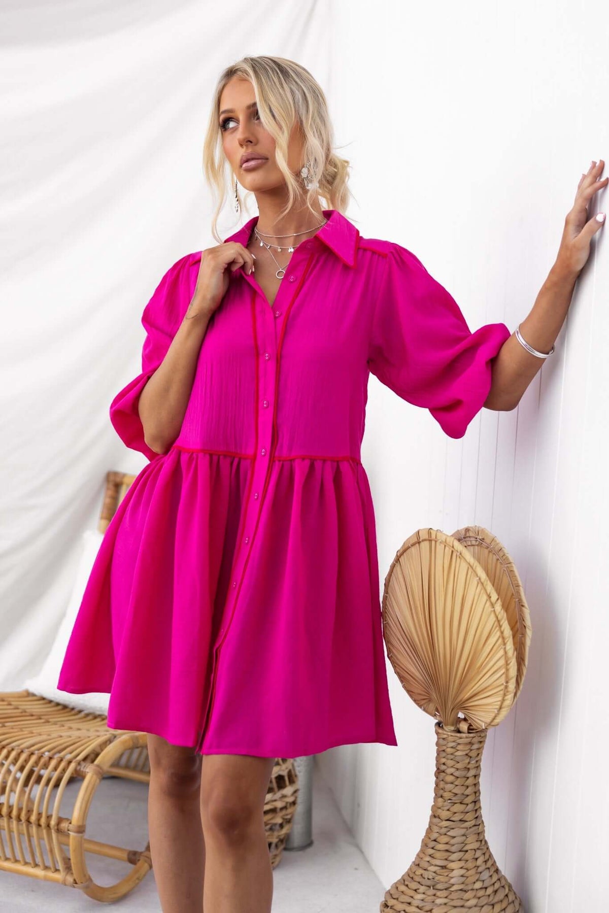 Stylish model wearing a pink Sherbet Dress with a button-down front and elastic sleeve hems, perfect for summer.