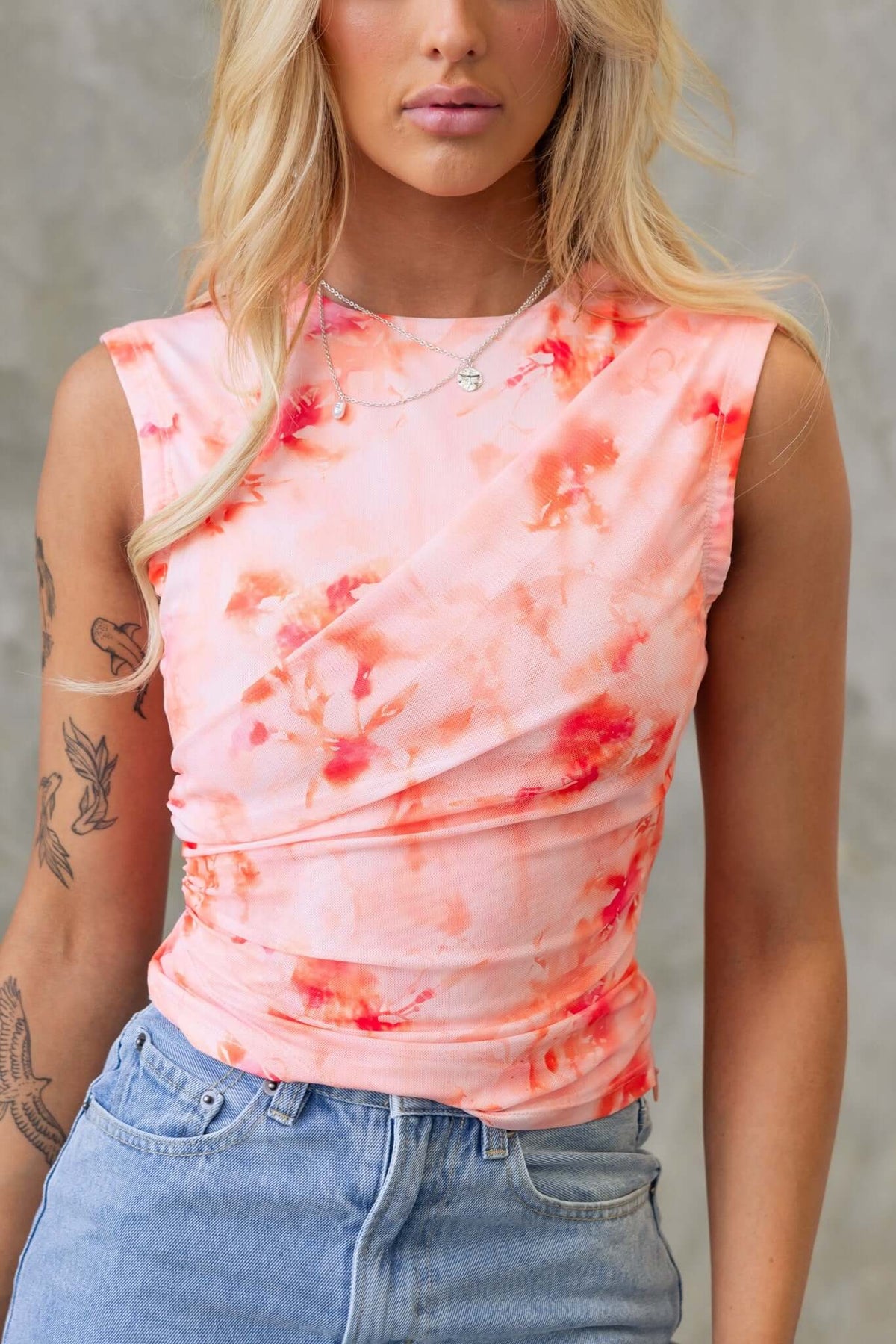 Cosmo Top featuring a round neckline, floral fabric overlay, and mesh material, styled with jeans.