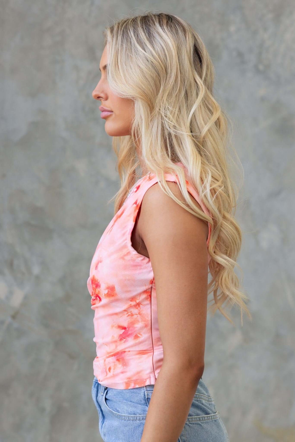 Profile view of a woman in a pink floral Cosmo Top, showcasing a round neckline and soft, stretchy material.