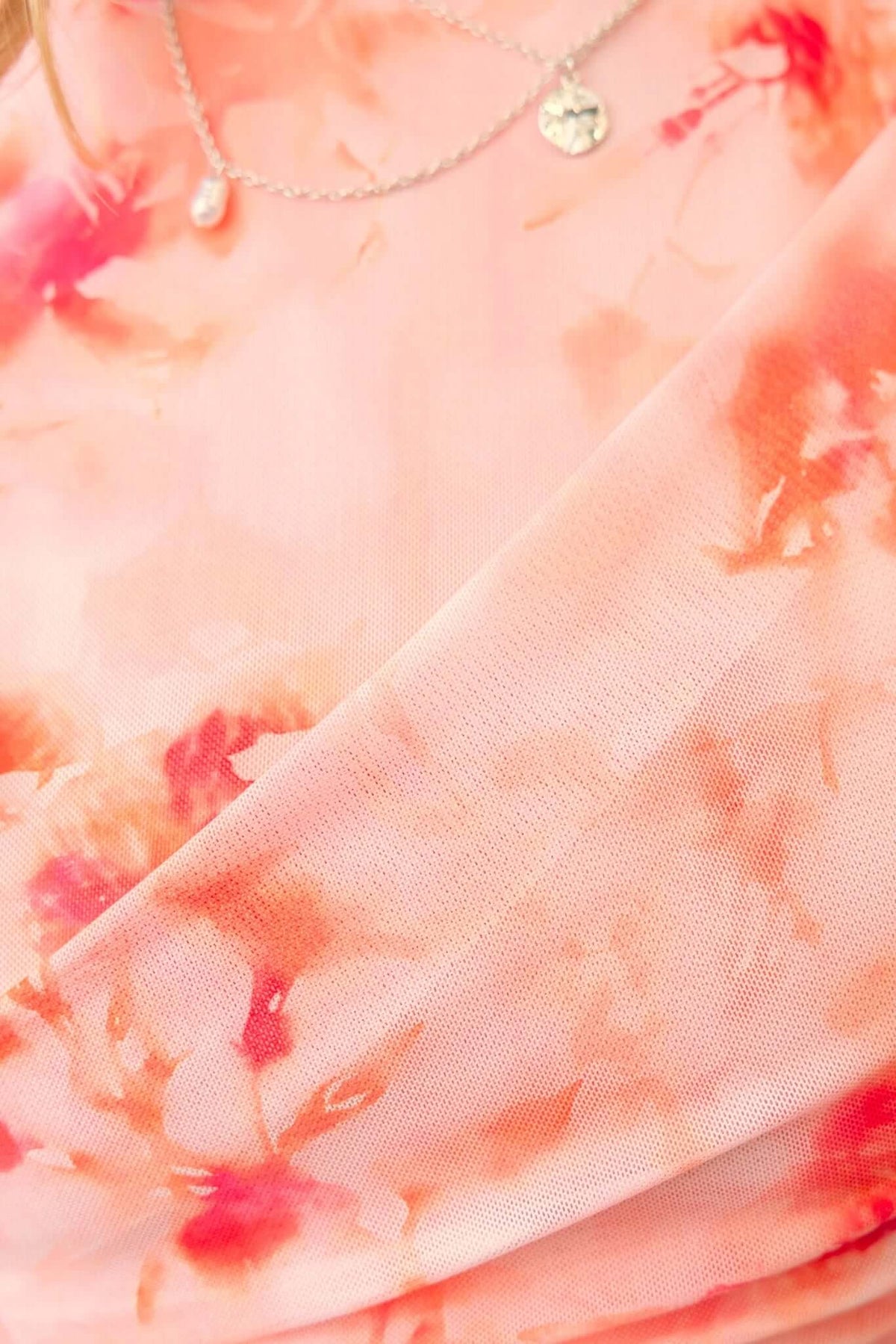 Close-up of Cosmo Top showing soft pink floral mesh fabric overlay with round neckline and delicate necklace.
