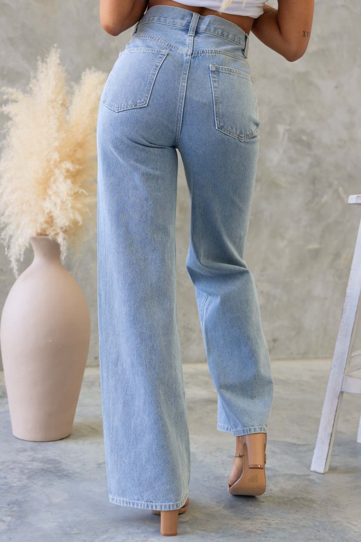 Rear view of a model wearing Claremont high waist, wide-leg jeans in light blue denim.