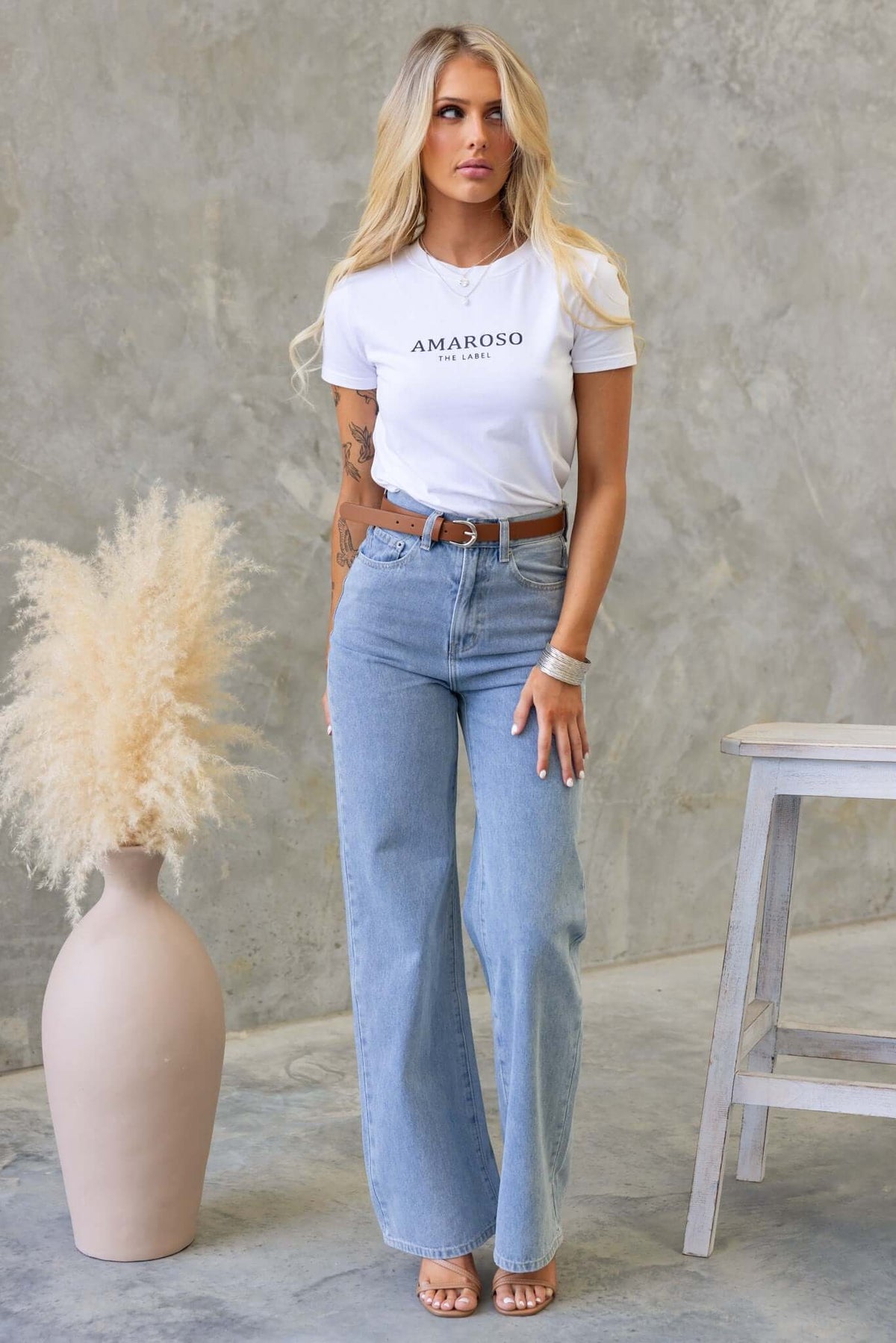 Model wearing Claremont jeans with a high waist fit and wide straight legs, paired with a stylish white t-shirt.