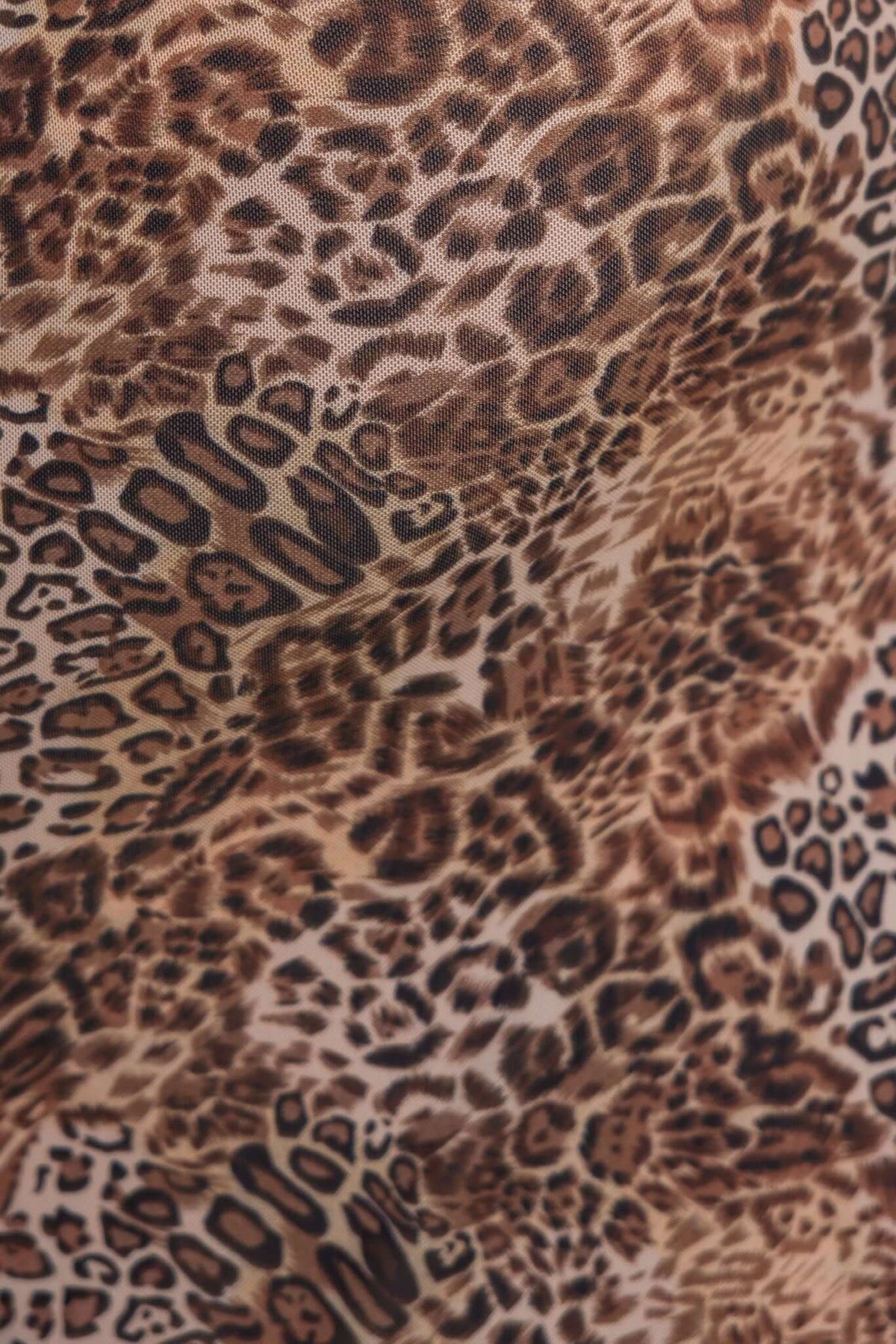 Close-up of leopard print fabric showcasing a mix of brown and black patterns, ideal for fashion design.