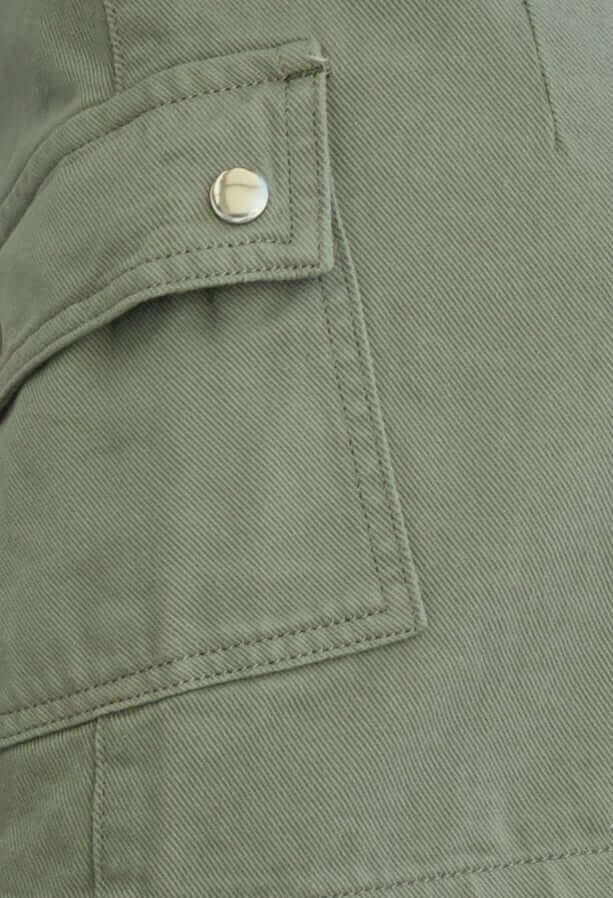 Detail of cargo pocket on an effortless denim skirt in olive green fabric, showcasing stitching and snap closure.