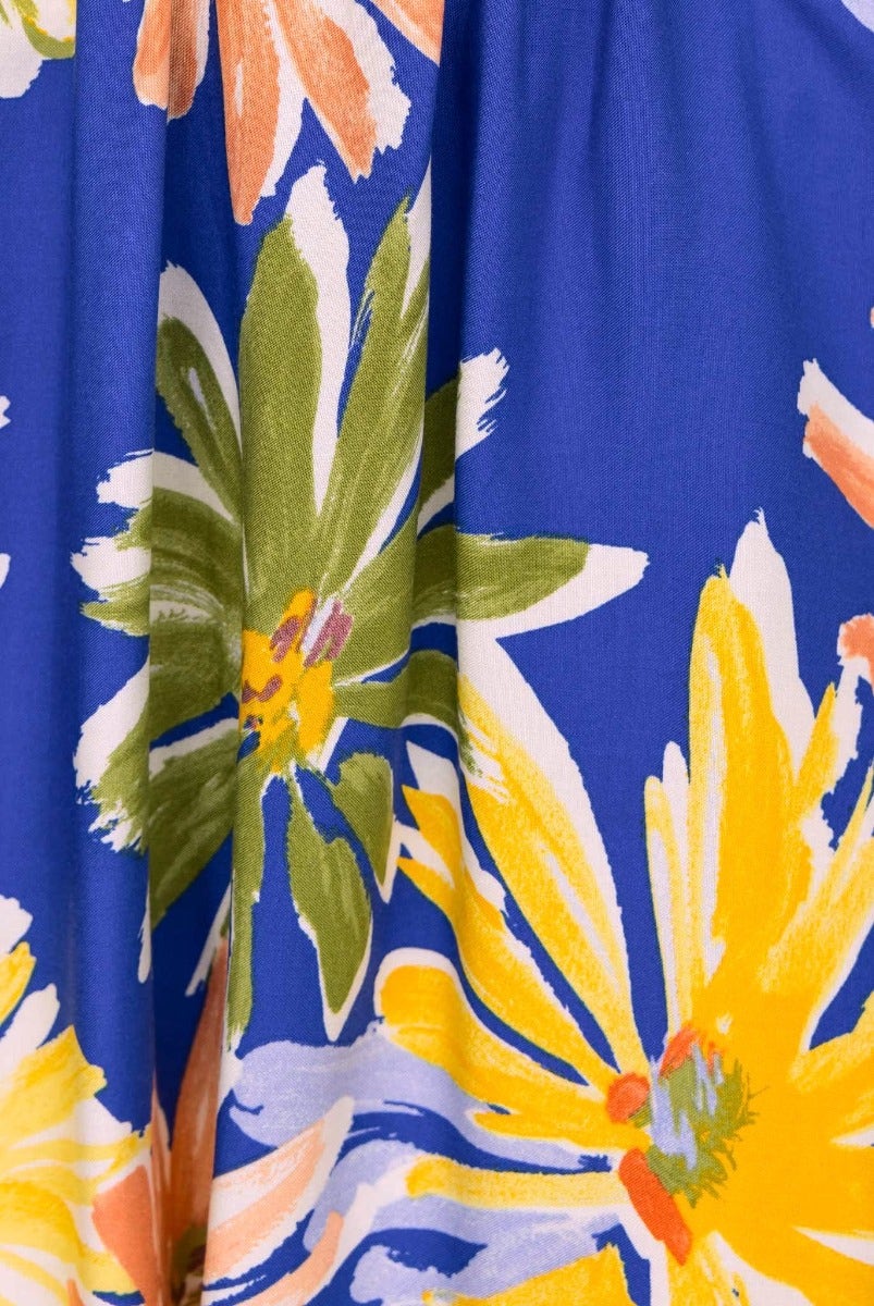 Close-up of bright floral print on blue fabric for the Haiti Dress, featuring yellow and green flowers.