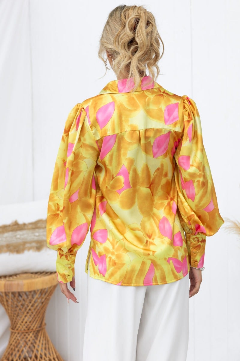 Back view of the Indianna Top featuring a satin finish, vibrant yellow and pink floral print, and puffy sleeves.