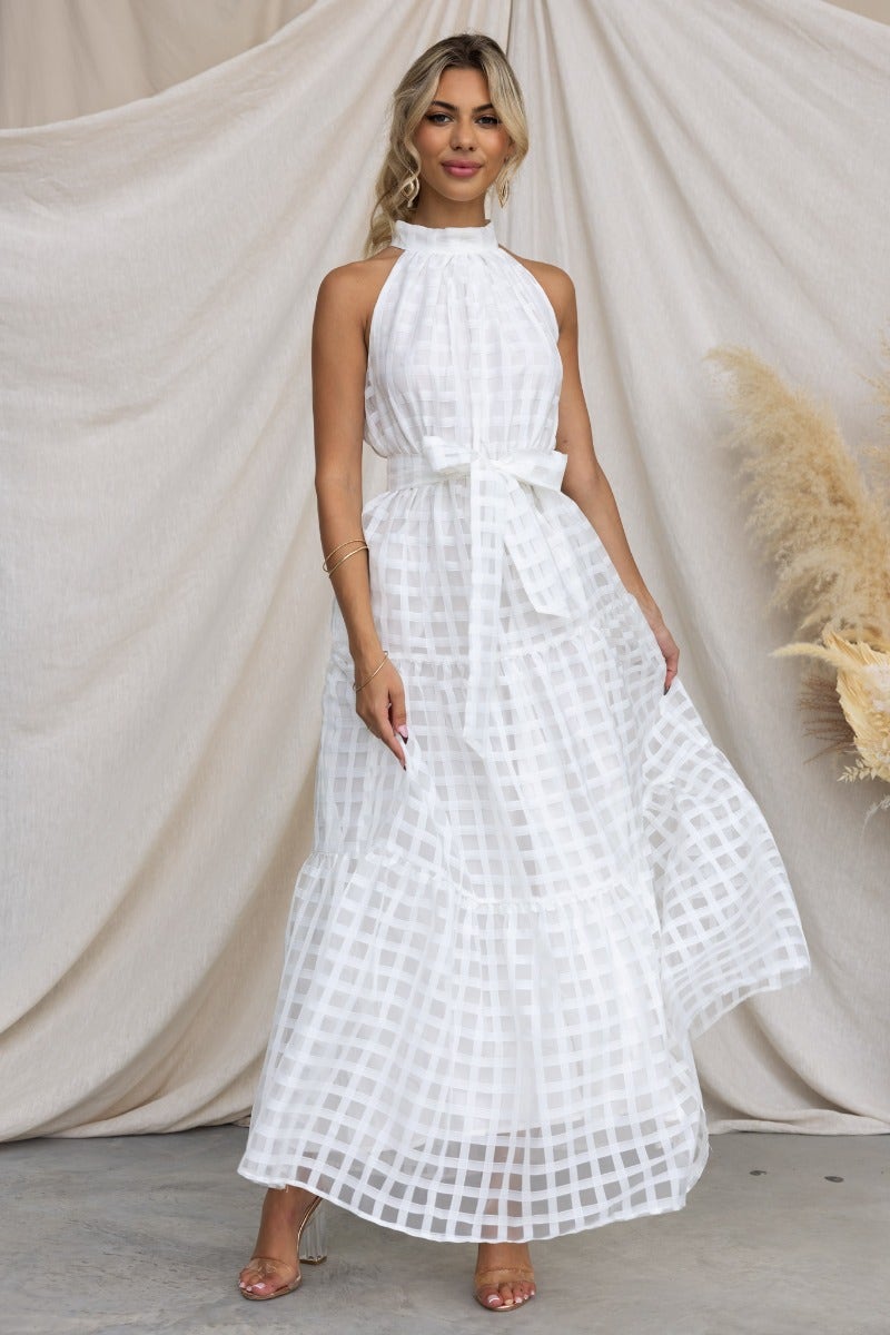 Aspiring maxi dress in white with high neckline, buttons, elastic waistband, and removable belt, styled elegantly.