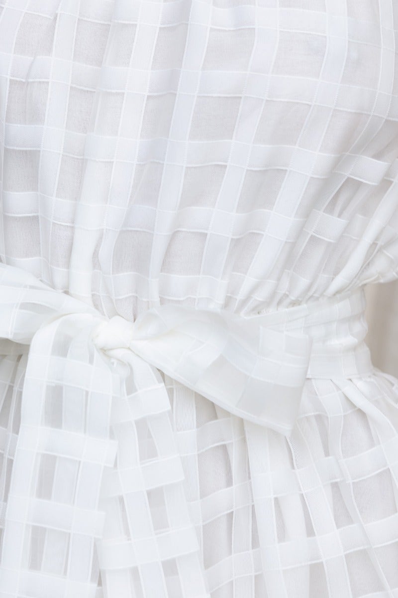 Close-up of white maxi dress featuring checkered pattern, elastic waistband, and removable fabric belt.