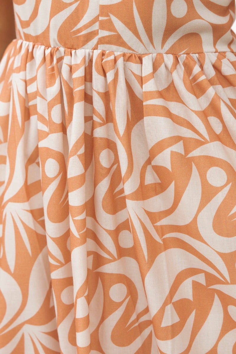 Close-up of the Vallere Maxi Dress in orange and white abstract pattern, featuring gathered fabric for a flowy fit.