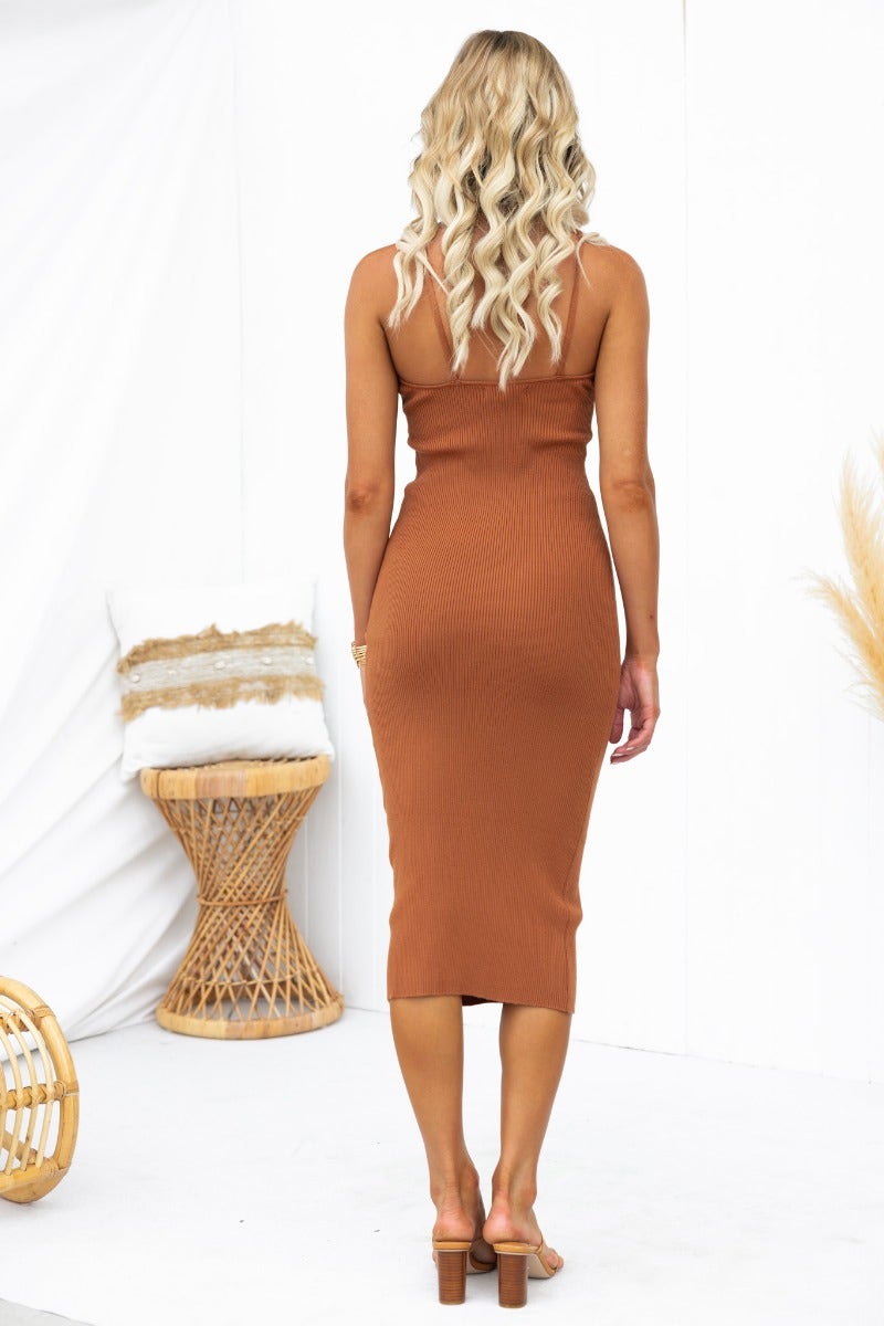 Back view of a woman in a ribbed knit Piah Midi Dress with halter neckline, tan color, showcasing a fitted silhouette.