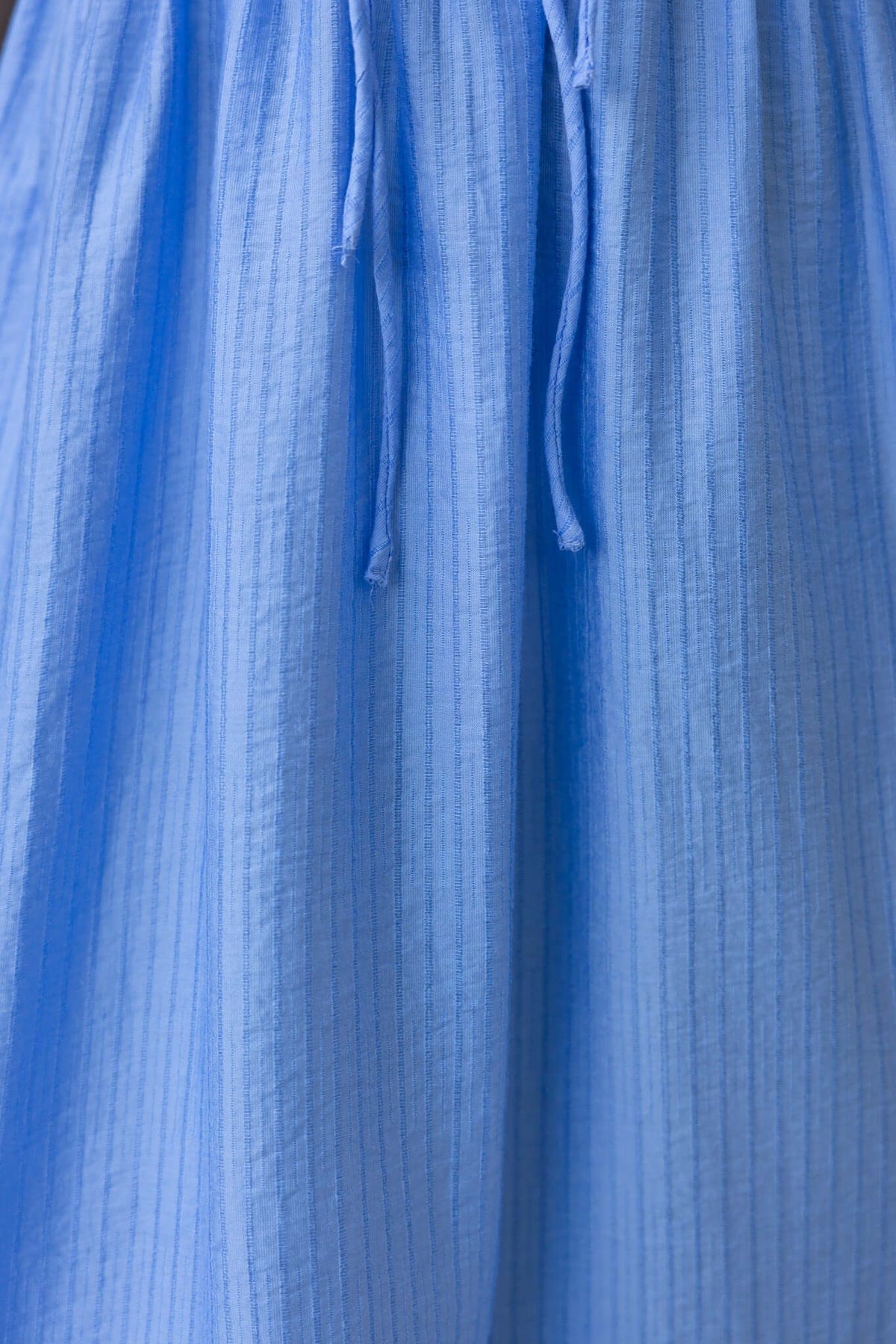 Close-up of textured blue midi dress fabric with elastic bodice and tie details.