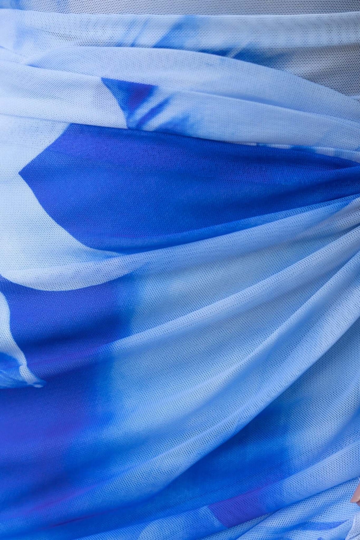 Close-up of blue and white mesh fabric showcasing a tie-dye pattern, highlighting the texture and draping of a maxi dress.