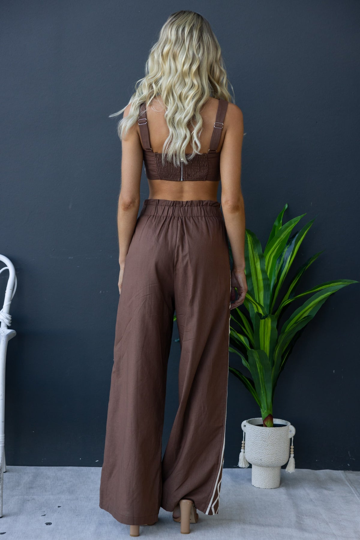 Back view of a woman in the Drisko Set featuring a top with adjustable straps and high-waisted pants in a linen look.