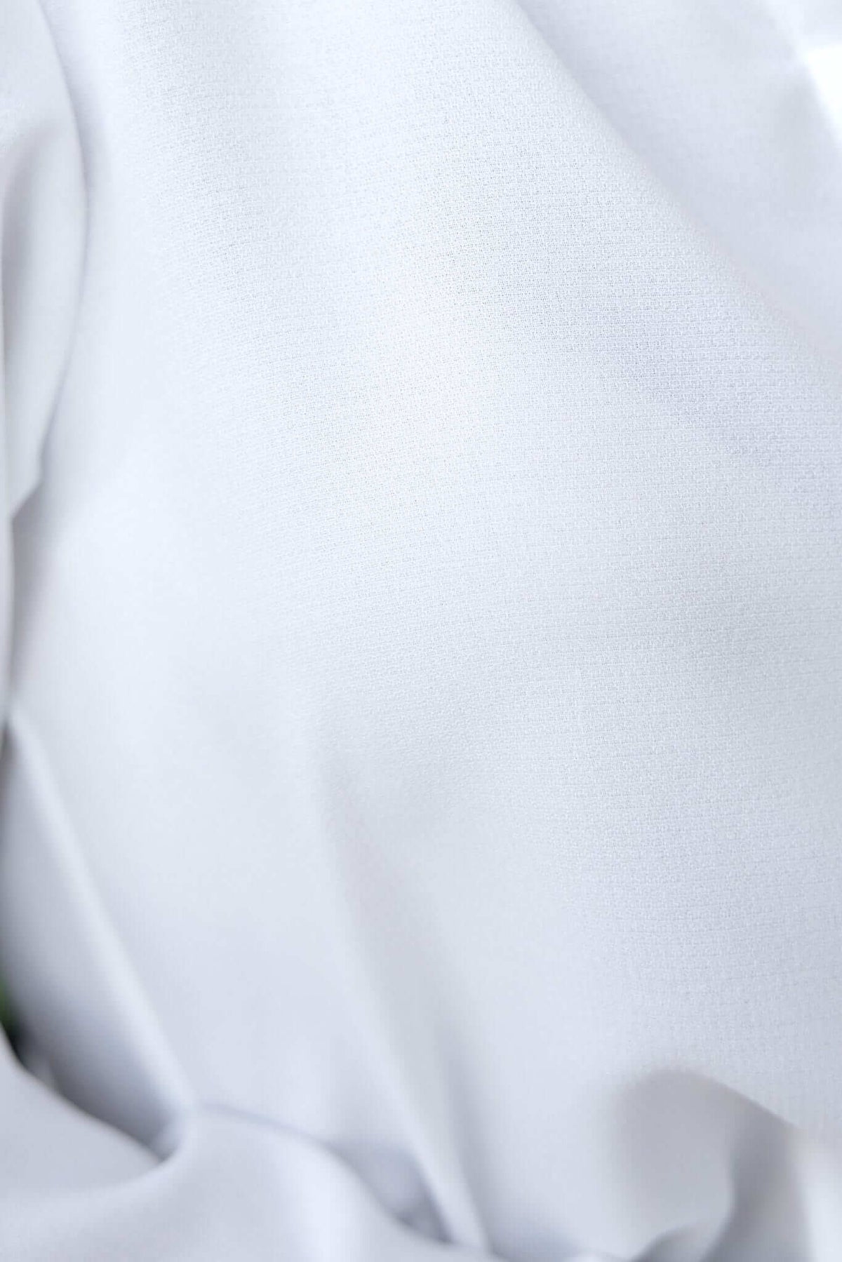 Close-up of the smooth, light material of the Toomba Shirt, showcasing its elegant white fabric texture.