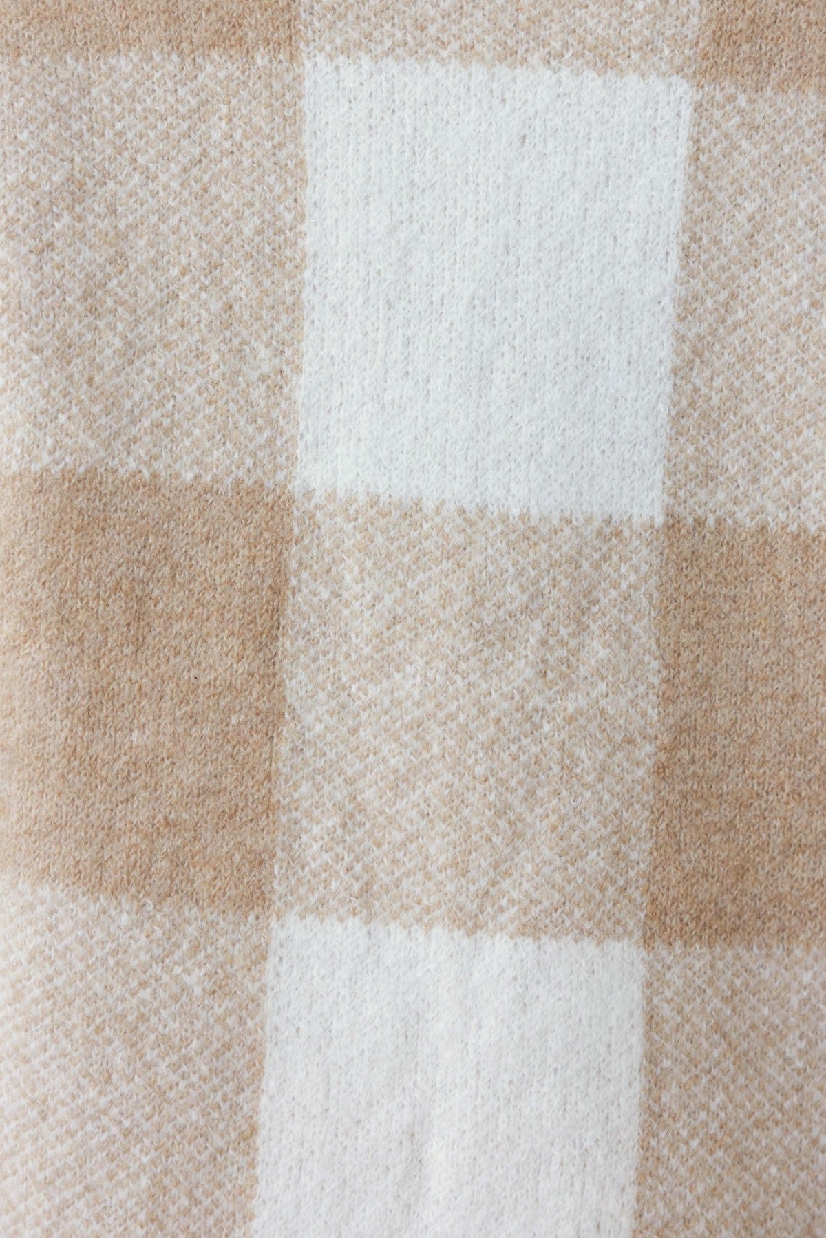 Close-up of beige and white plaid fabric texture, perfect for cozy cardigans and warm clothing.
