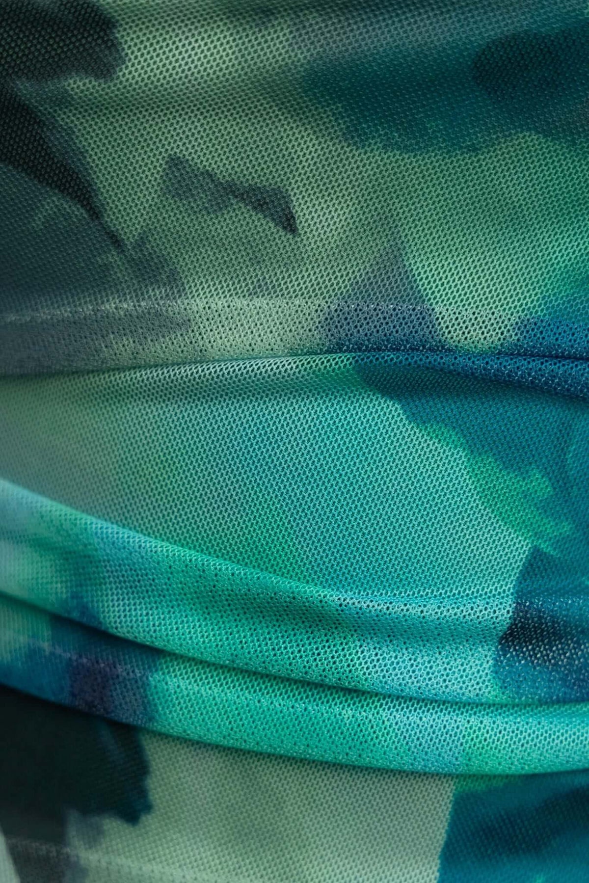 Close-up of Talinga Midi Dress fabric featuring teal mesh with artistic watercolor pattern, showcasing its quality and texture.