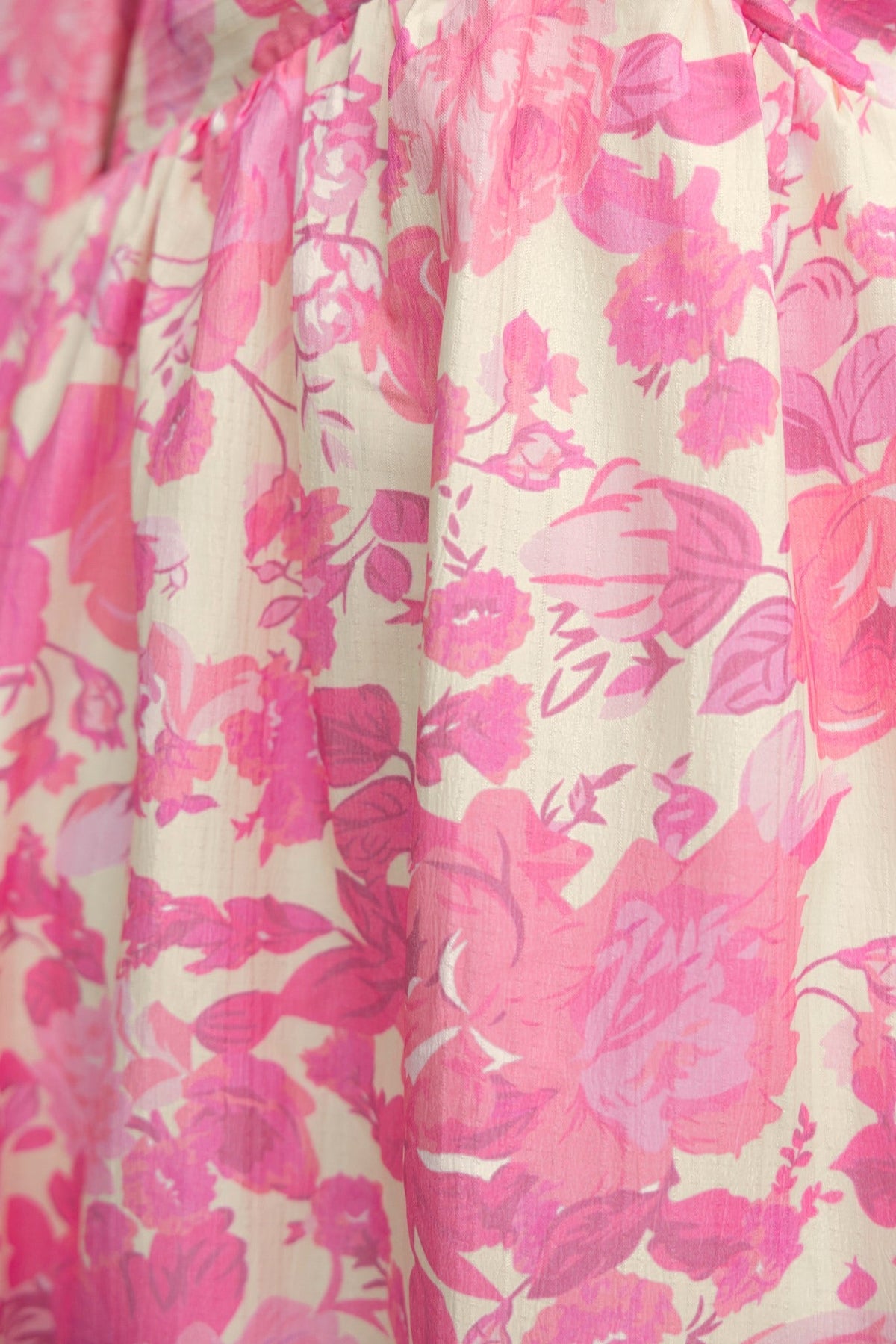 Close-up of pink floral pattern on the fabric of a maxi dress, showcasing vibrant colors and fine details.