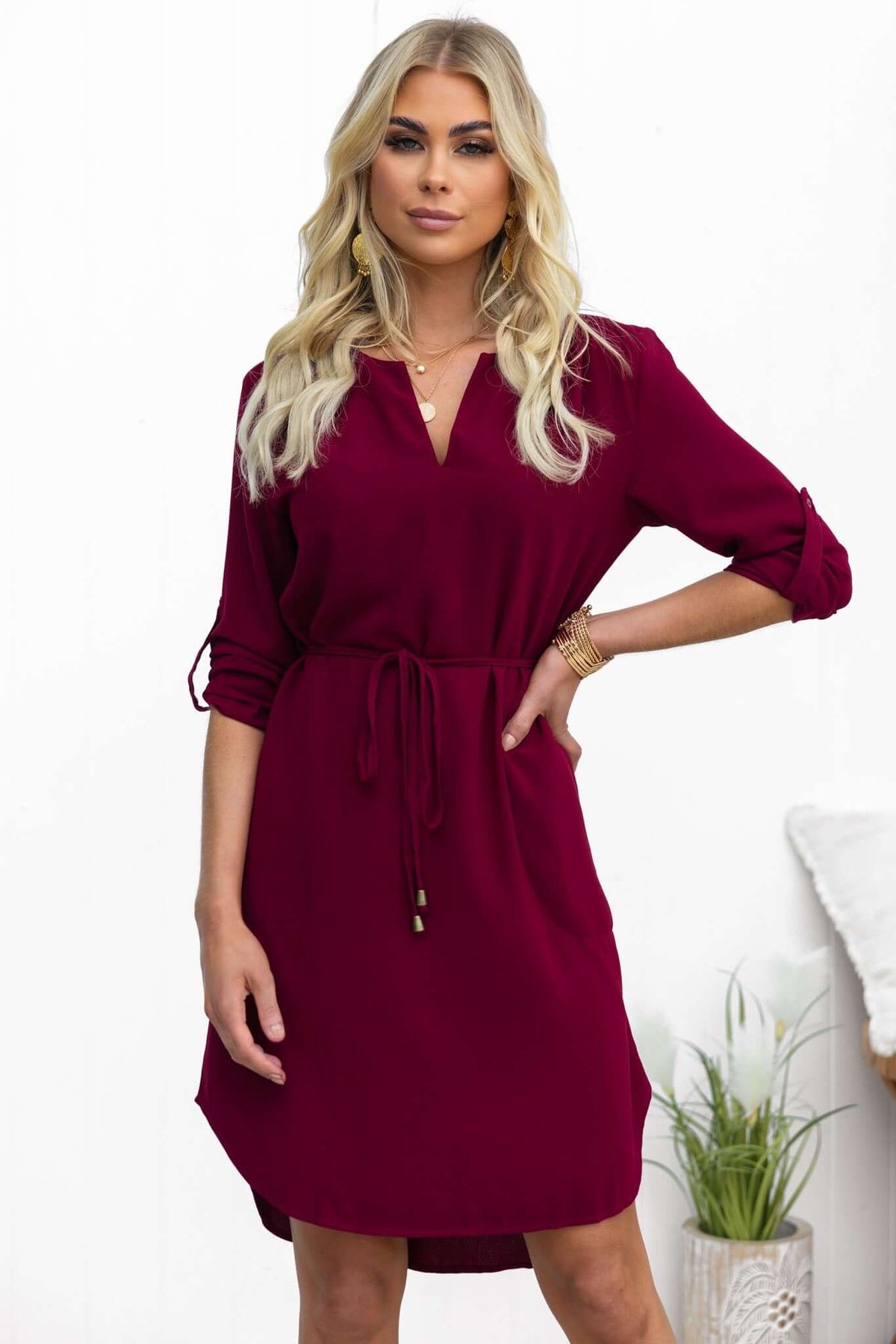 Model wearing a burgundy Deklyn dress with a V-neckline, removable tie, and pockets, styled for casual elegance.