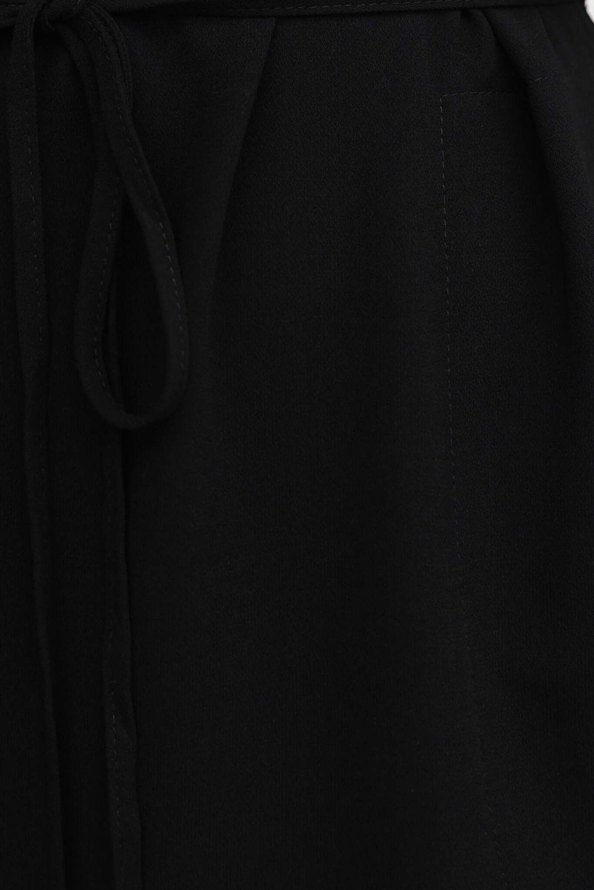 Close-up of Deklyn Dress showing black fabric with tie detail and pocket, showcasing its stylish design.