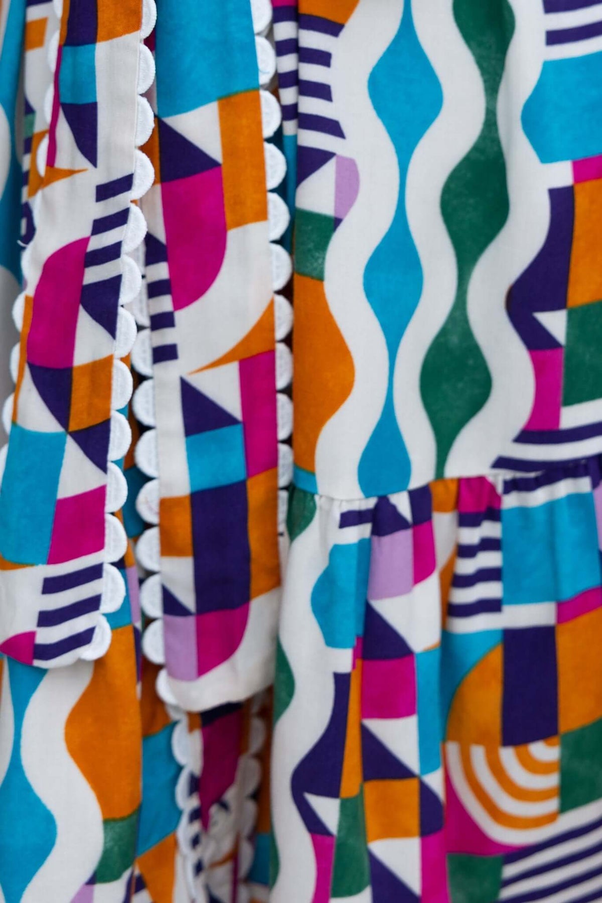 Close-up of Bransley Dress featuring vibrant geometric patterns and scalloped detailing.
