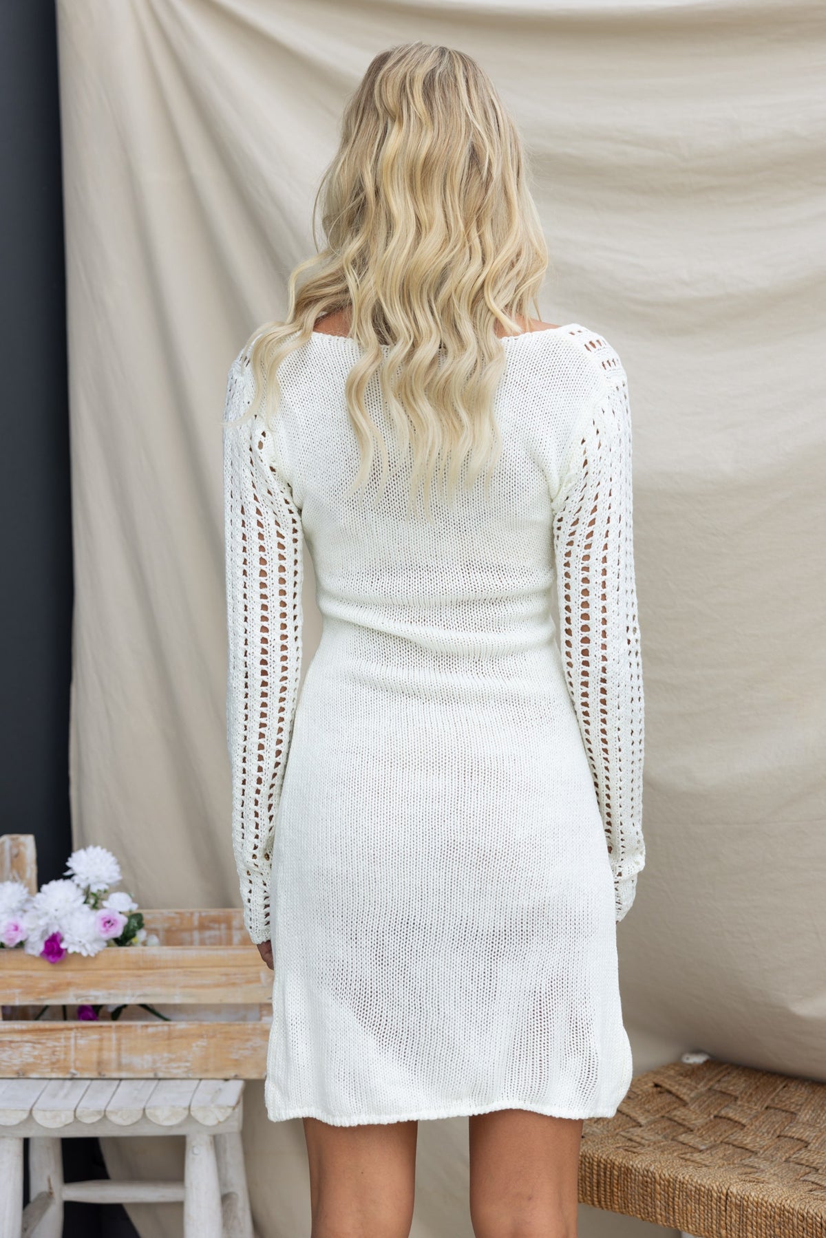 Back view of a woman in a white crochet Lilou Dress featuring twist detail and long sleeves.
