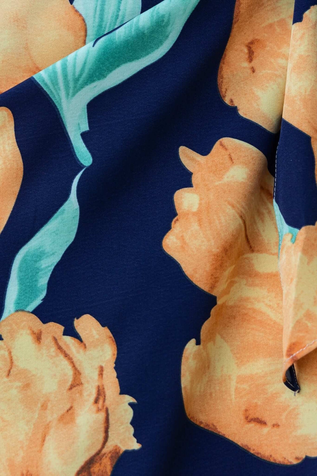 Close-up of floral fabric featuring vibrant orange flowers on a navy background for the Diri Maxi Dress.